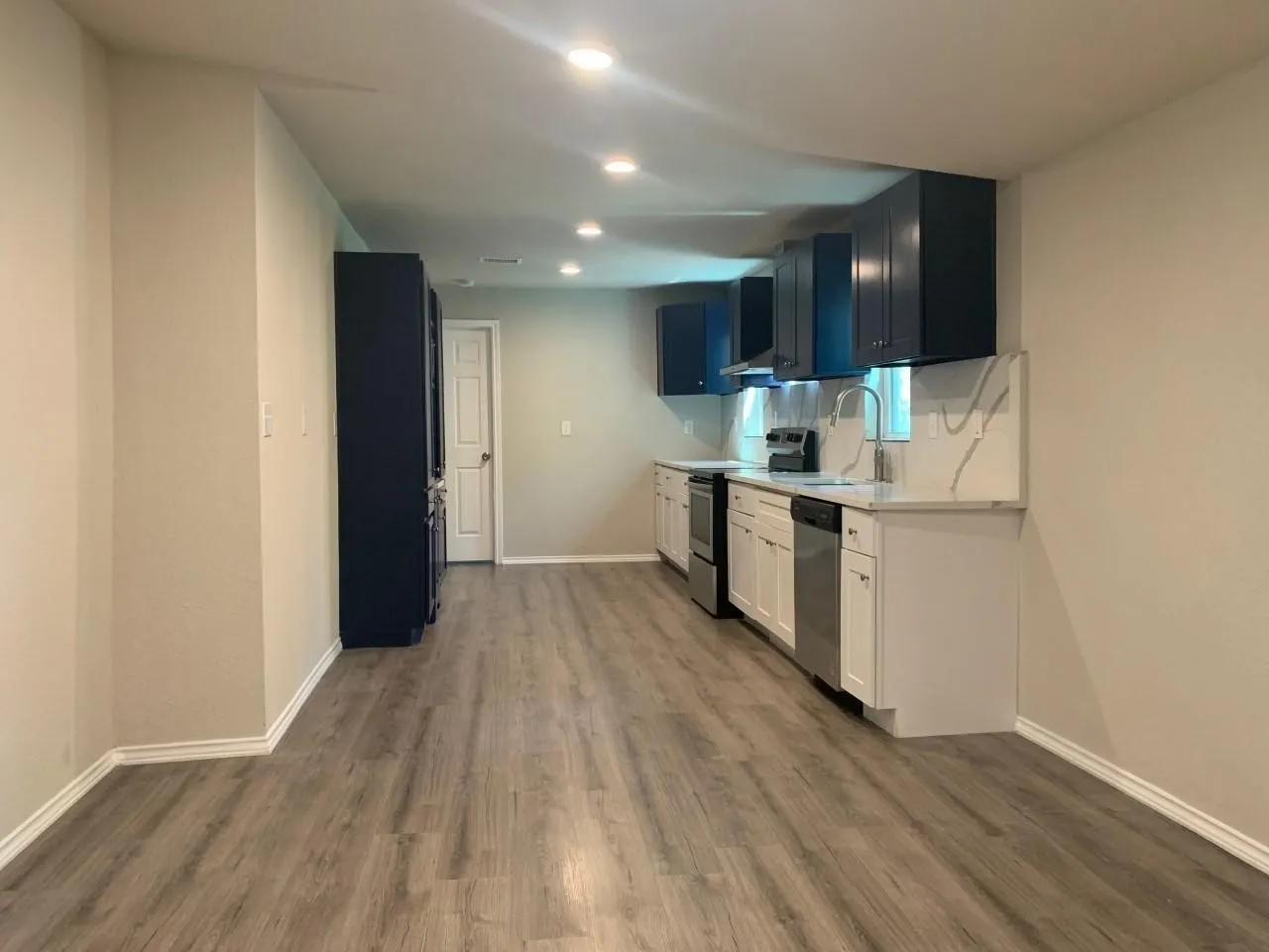 Kitchen featuring wood-finish flooring, recessed lighting, two-tone cabinetry, stainless steel appliances, and a solid surface countertop with a matching backsplash
