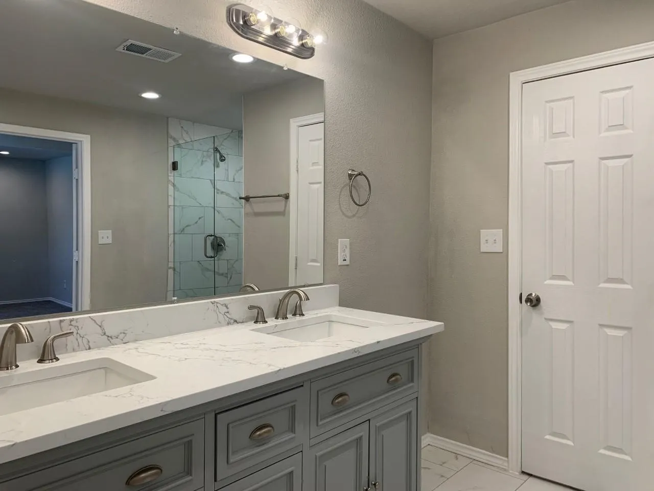 Dual vanity with a white countertop, under-mount sinks, and brushed nickel faucets