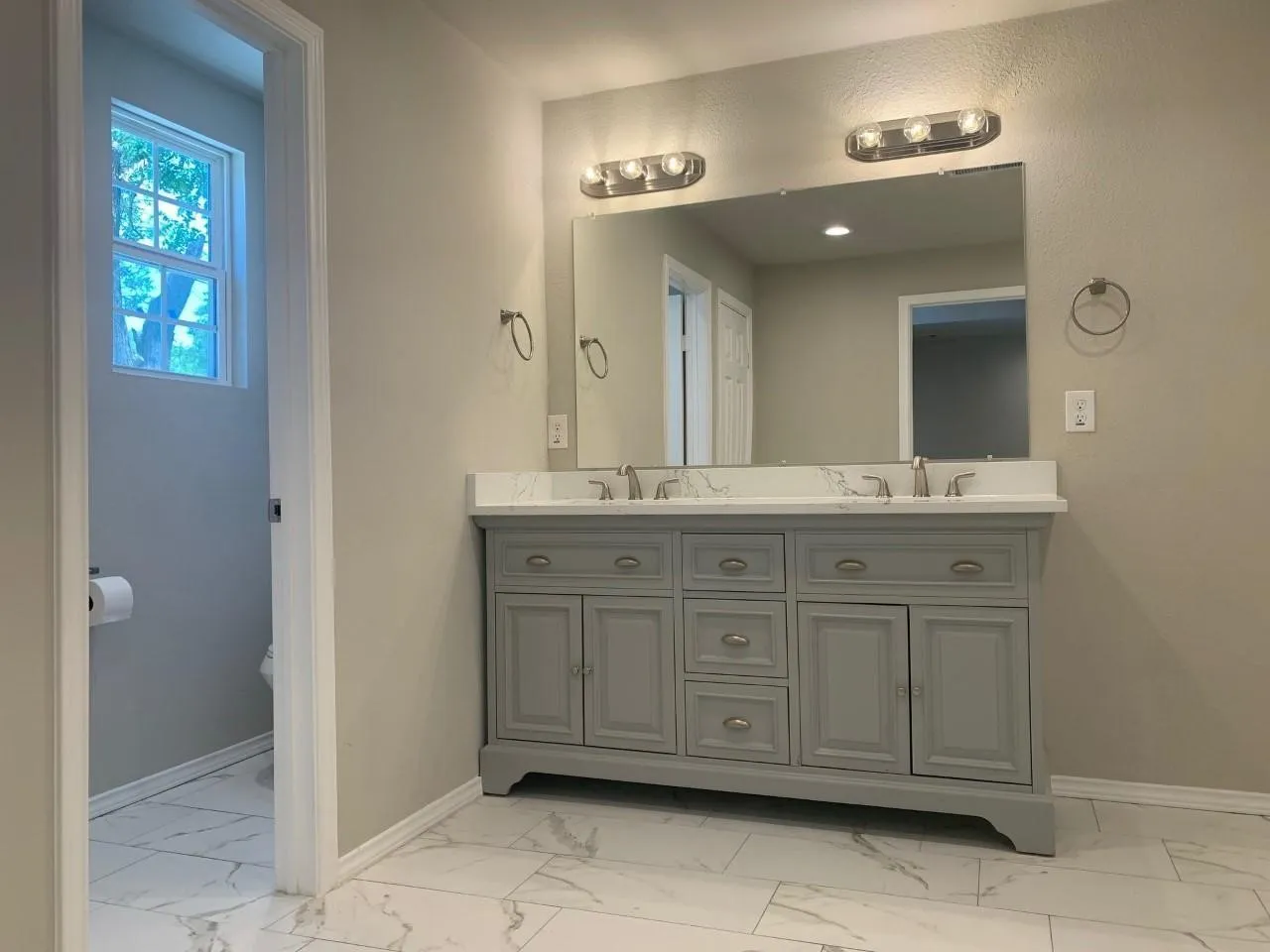Double vanity with light gray cabinetry, brushed nickel hardware, and a white marble-look countertop