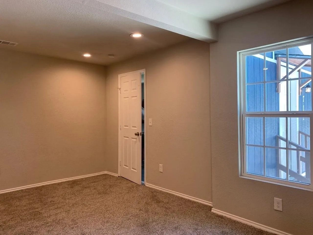 Recessed ceiling lighting, paneled interior door, window with grid pattern, neutral-toned walls, and carpet flooring