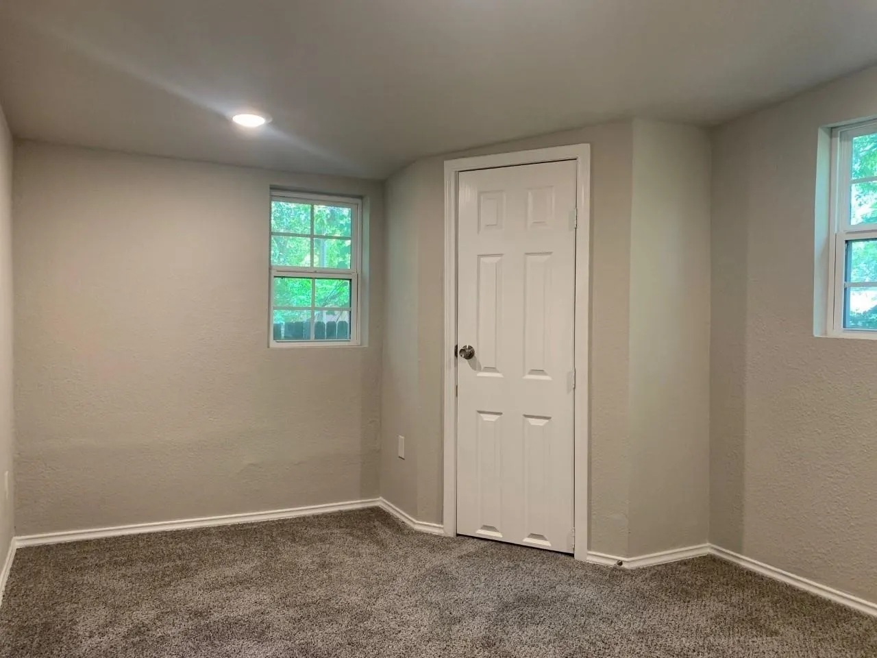 Recessed ceiling lighting, paneled interior door, two windows, textured wall finish, and carpeted flooring