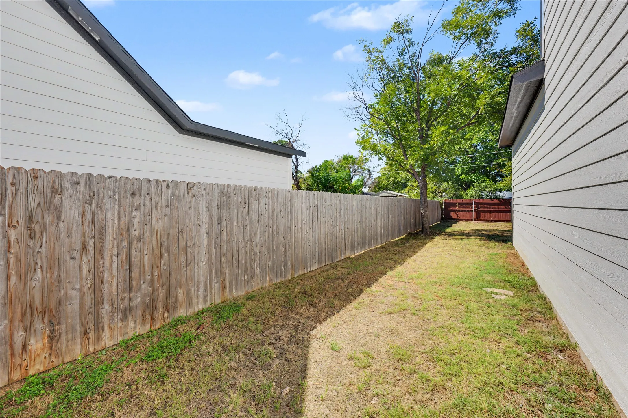 Expansive side yard featuring a wood fence and established trees