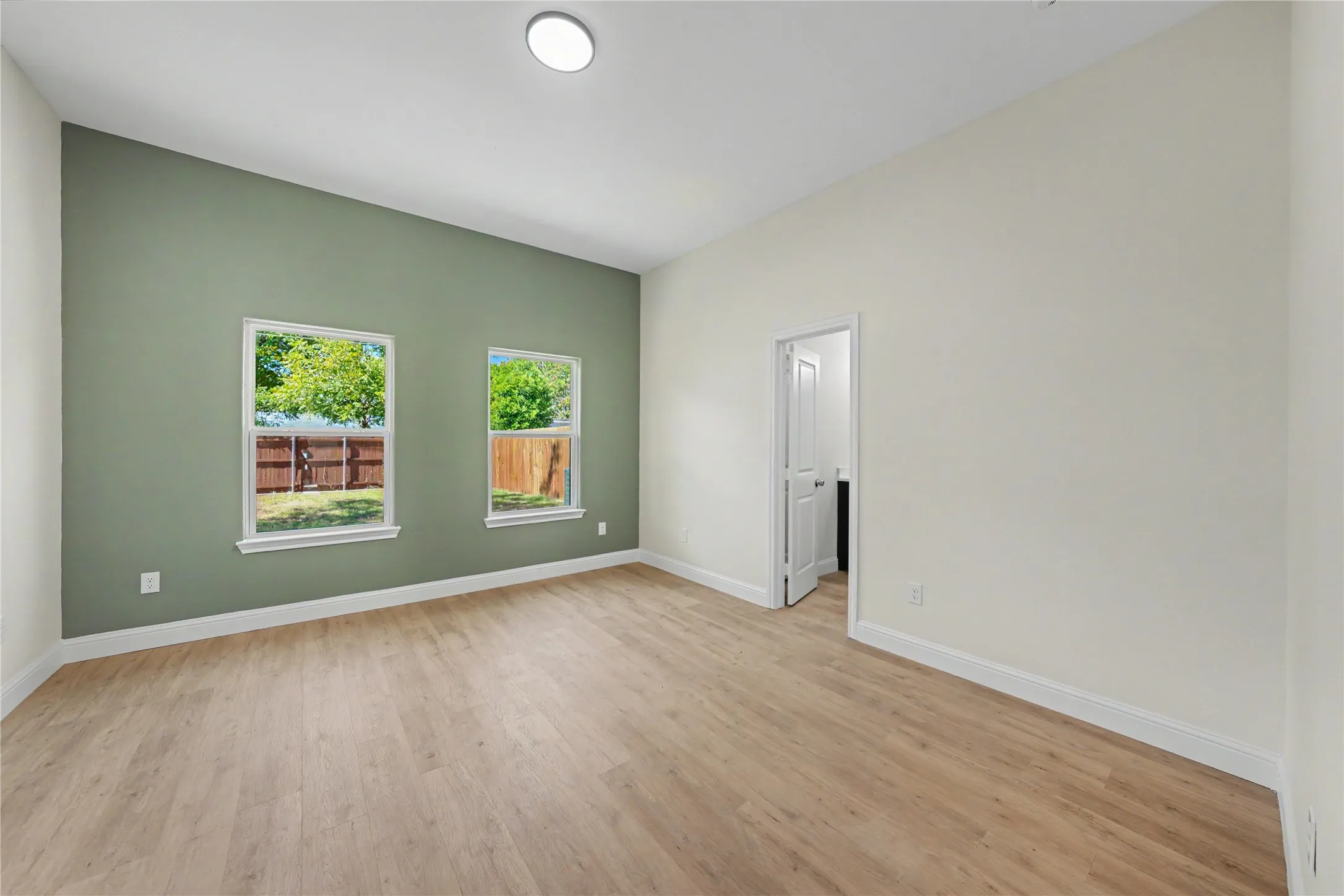 Light wood-finish flooring, recessed ceiling lighting, a prominent accent wall, and two windows