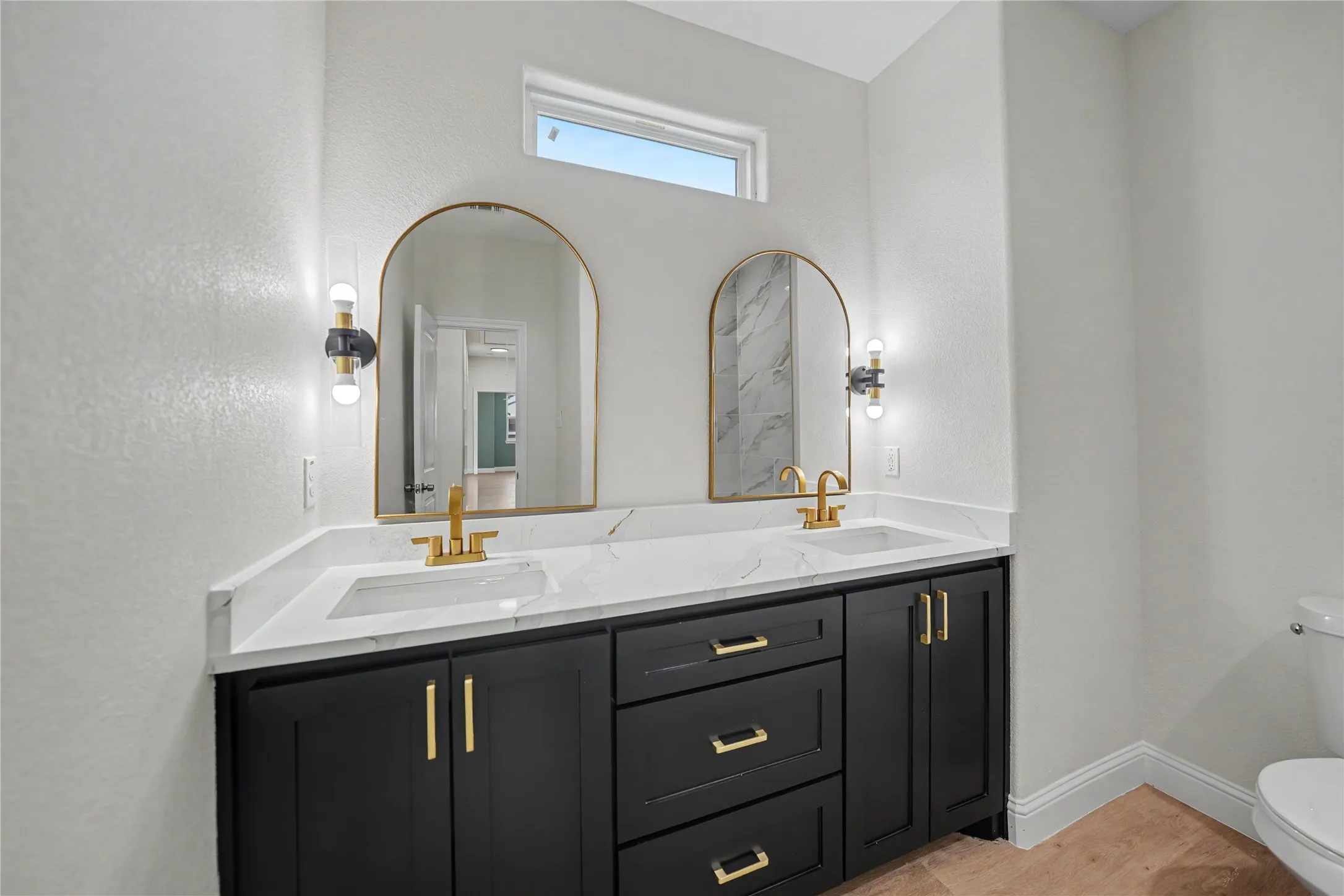 Double vanity with black cabinetry, gold-finish hardware, and a white countertop