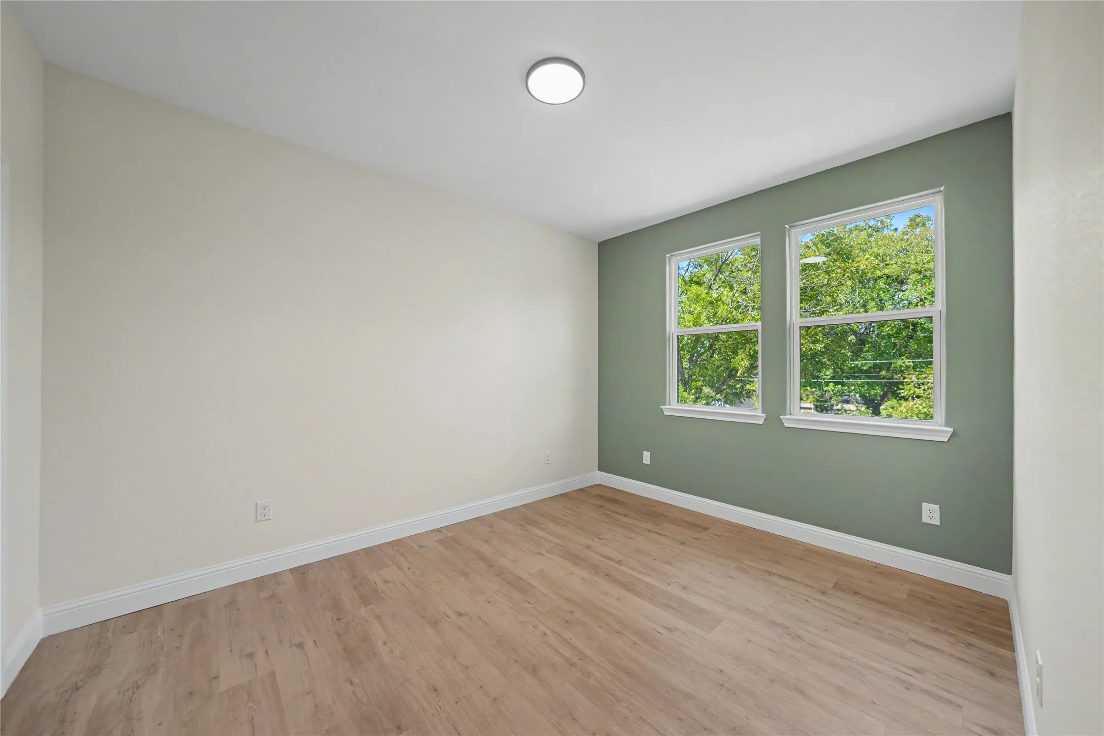 Upstairs bedroom featuring wood-finish flooring, recessed ceiling light, dual windows, and a contrasting accent wall