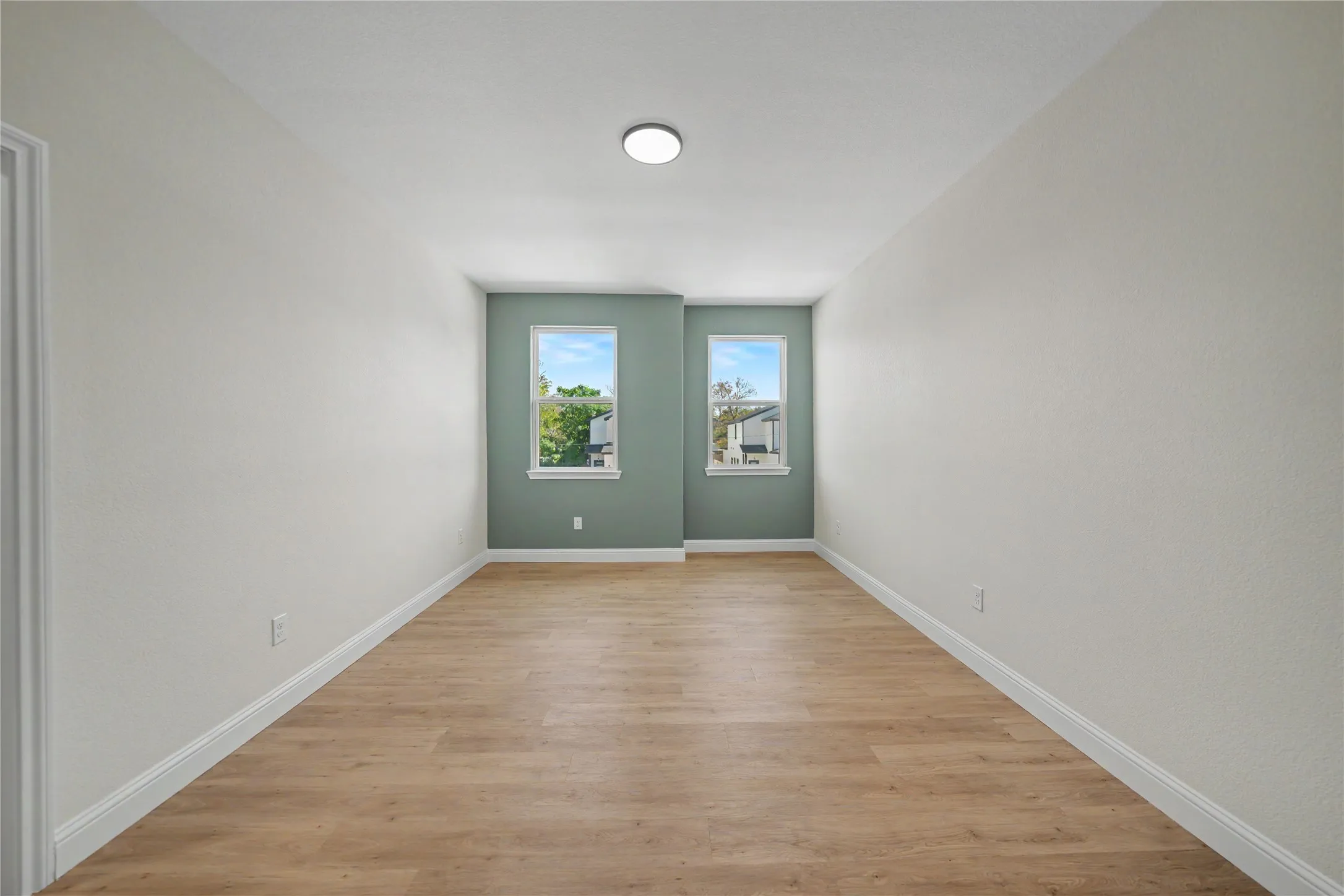 Wood-finish flooring, recessed lighting, and dual windows with white trim