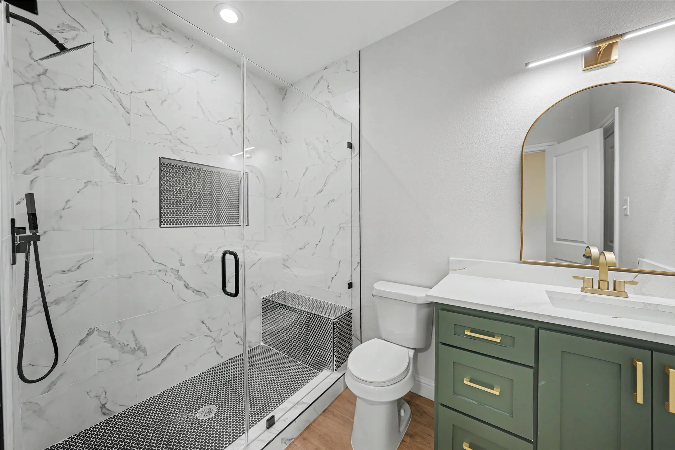 Walk-in shower with clear glass enclosure and black-and-white tile accents