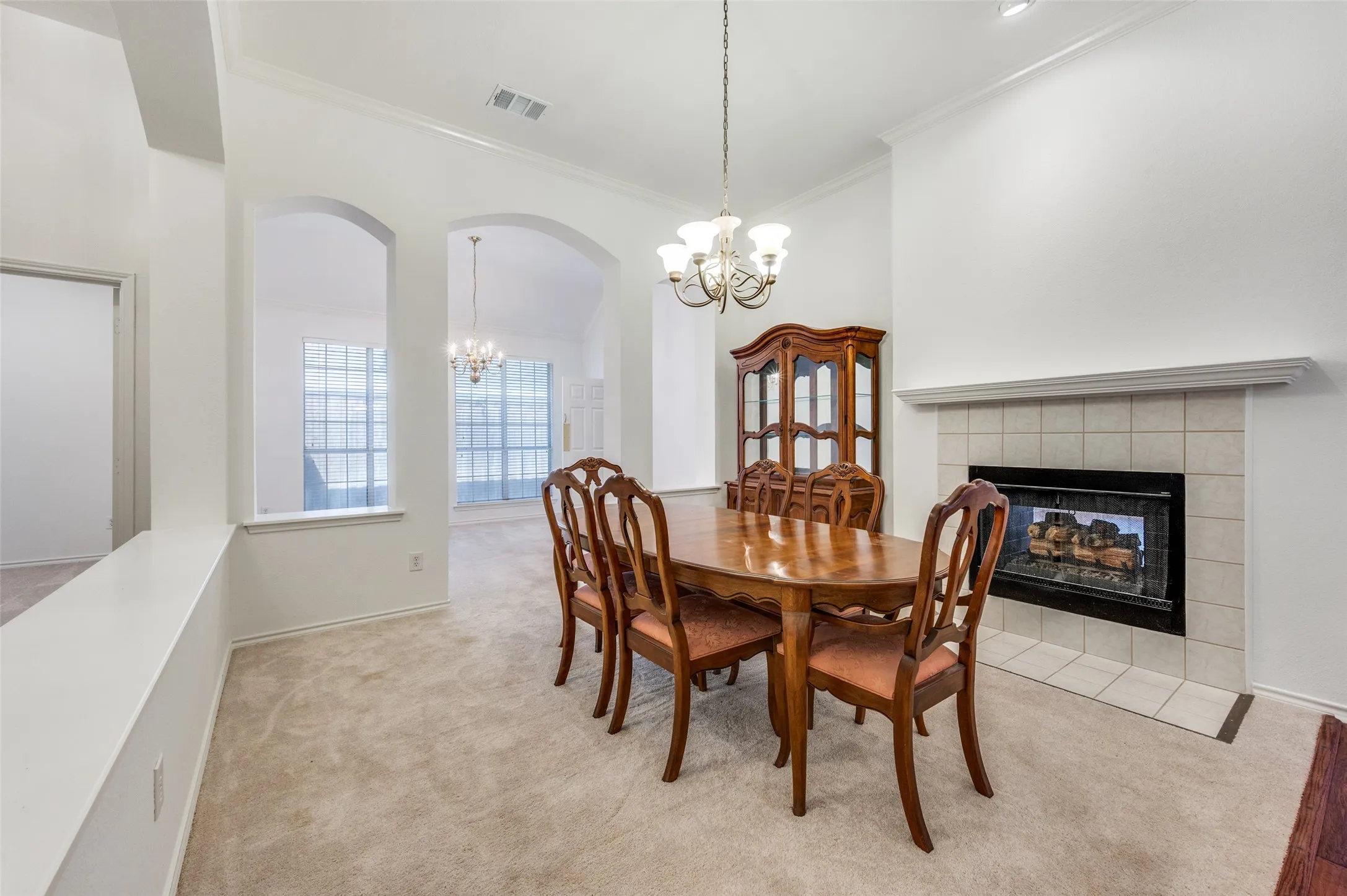 Tiled fireplace with a mantel, arched doorways, and a chandelier lighting fixture