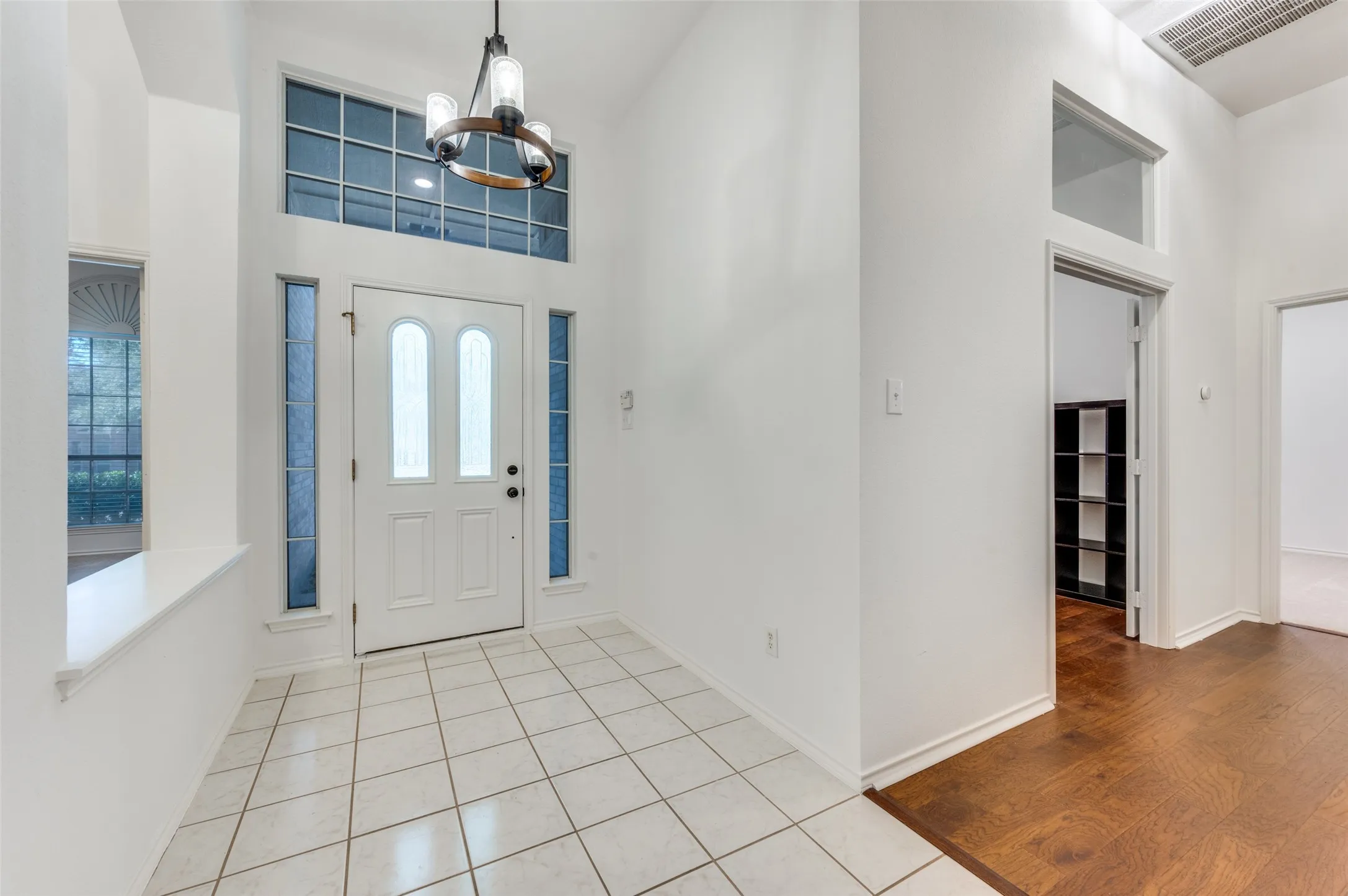 Two-story foyer featuring a white paneled entry door, sidelight windows, and a transom window