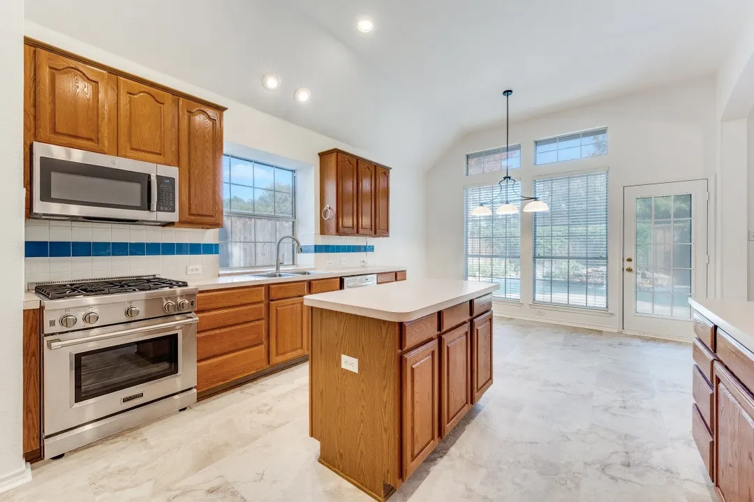 Kitchen featuring wood cabinetry, stainless steel appliances, a center island, and a door leading to the exterior
