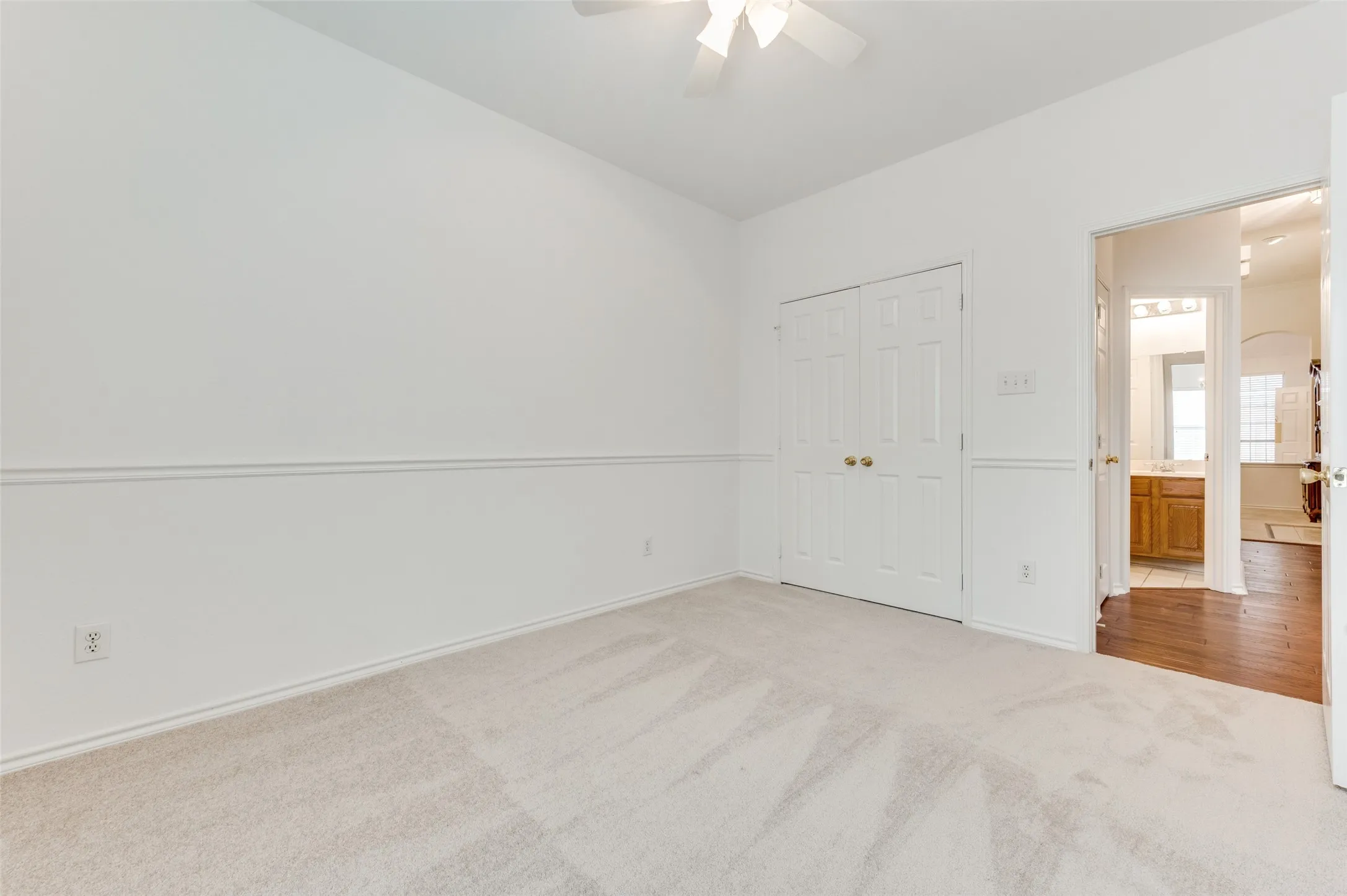 One of two bedrooms located on the east side of the home.  Neutral tone carpeting and white painted walls with chair rail molding