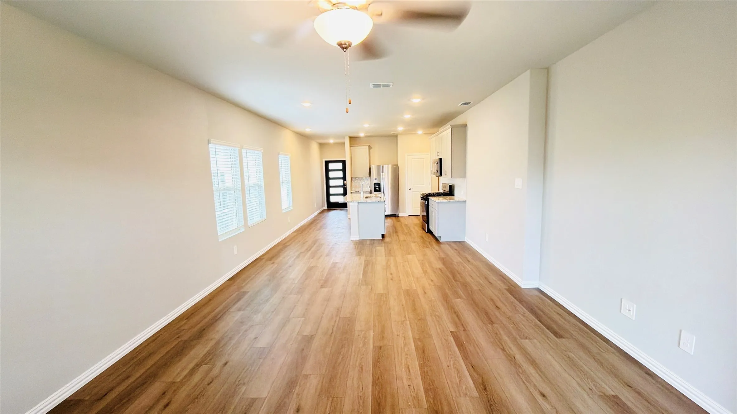 Spacious living area featuring wood-finish flooring, recessed lighting, and a ceiling fan