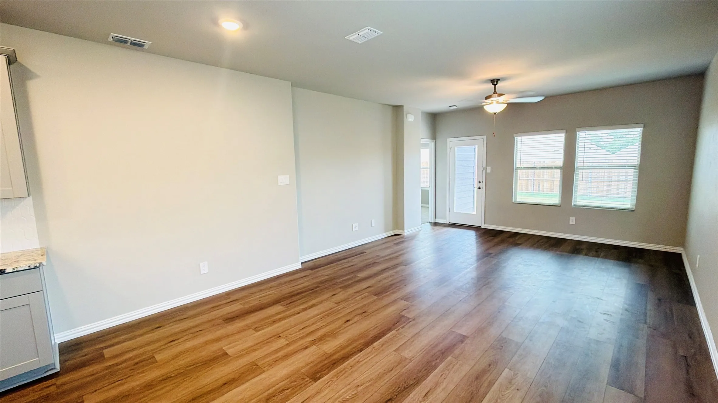 Expansive room featuring wood-finish flooring, multiple windows, a ceiling fan, and recessed lighting