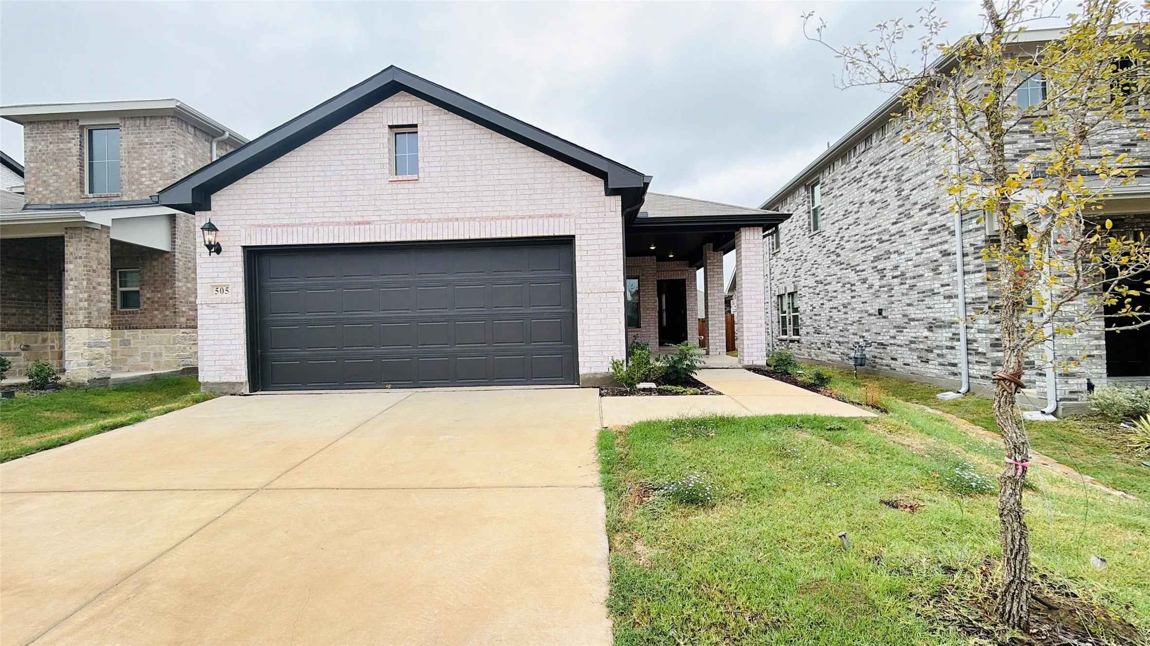 White brick exterior with dark trim and a dark garage door