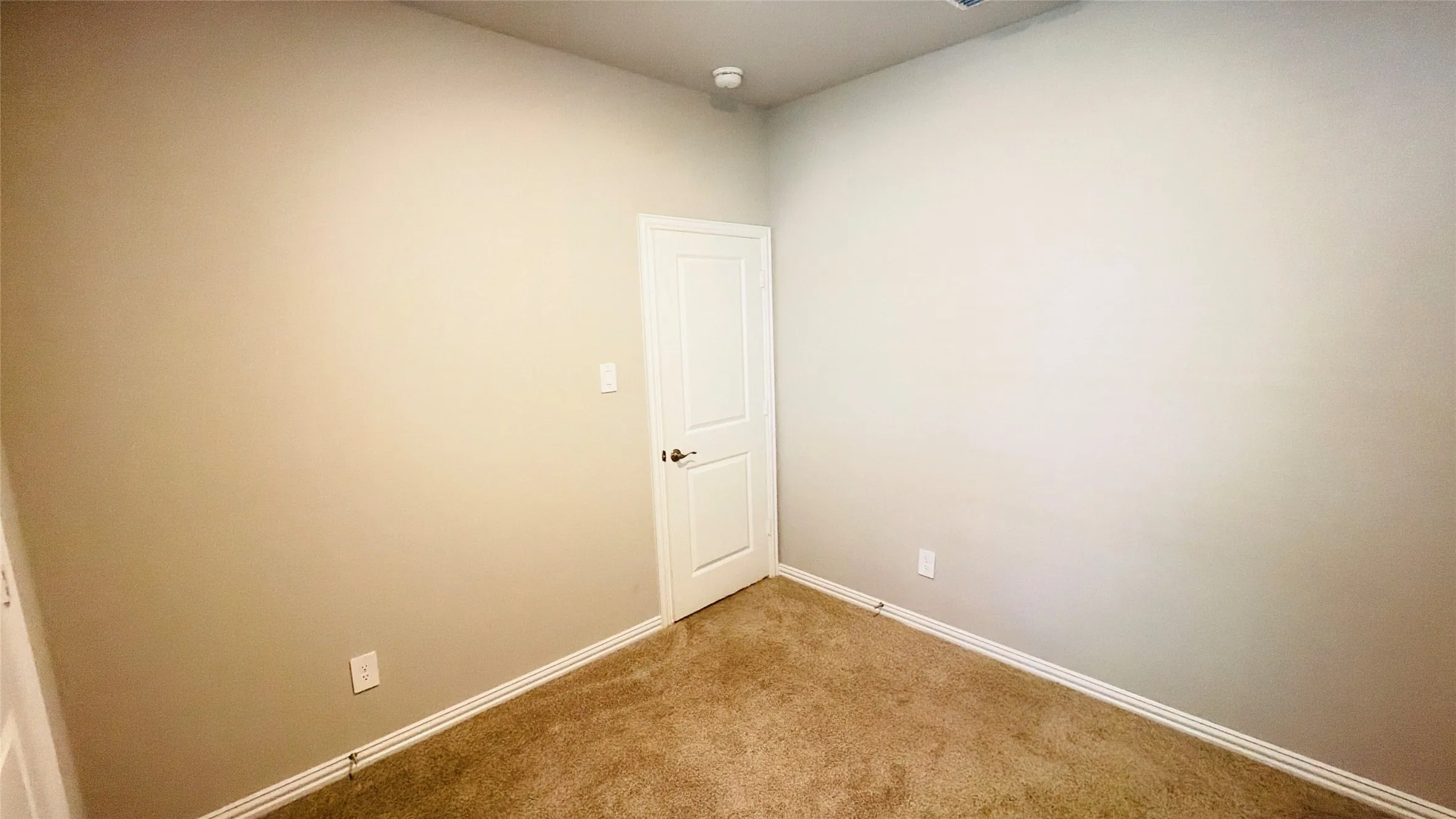 Carpeted flooring, light-colored walls, white trim, and a white door with a dark handle