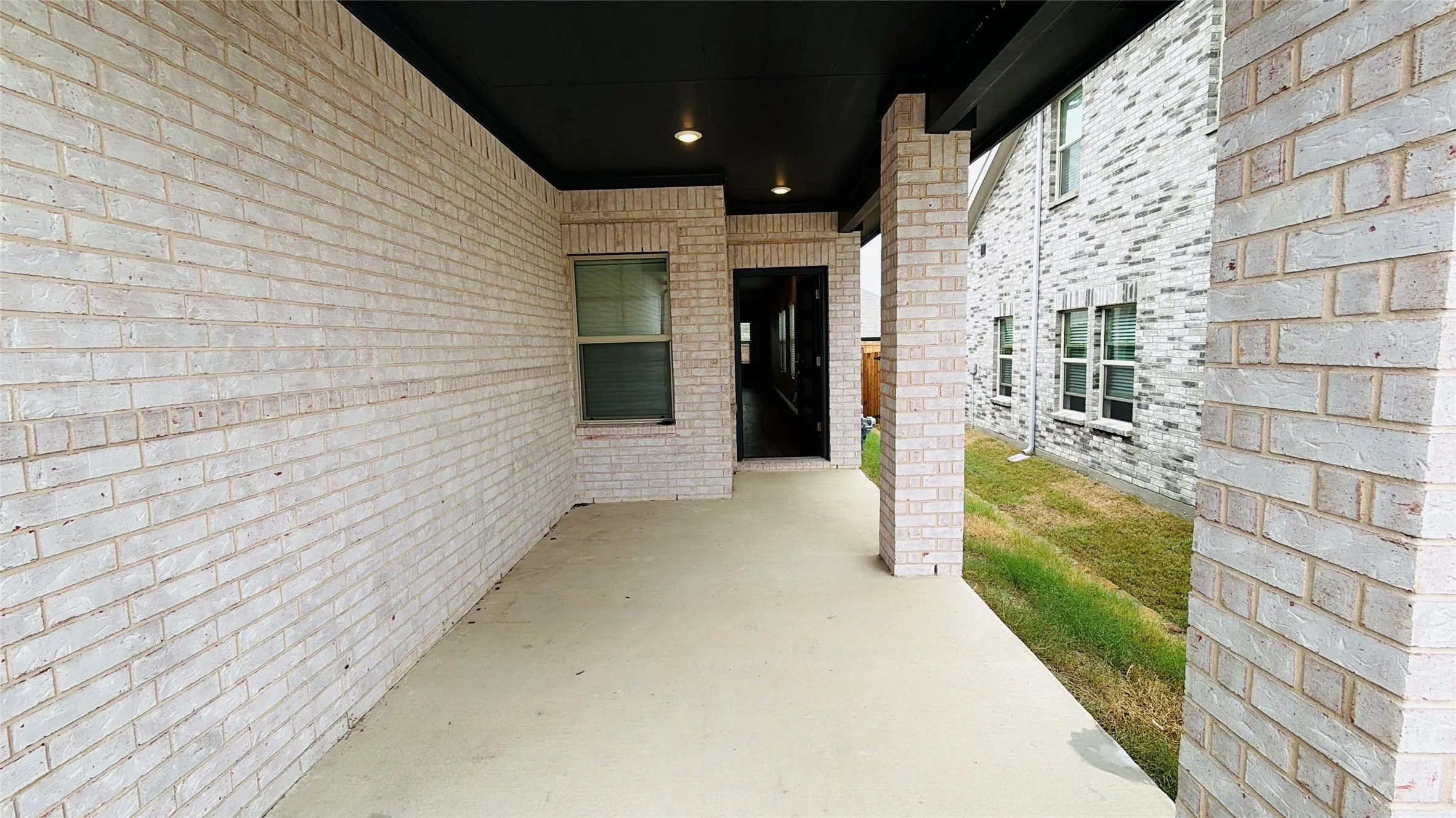 Covered patio featuring a concrete slab, recessed lighting, and a white brick exterior