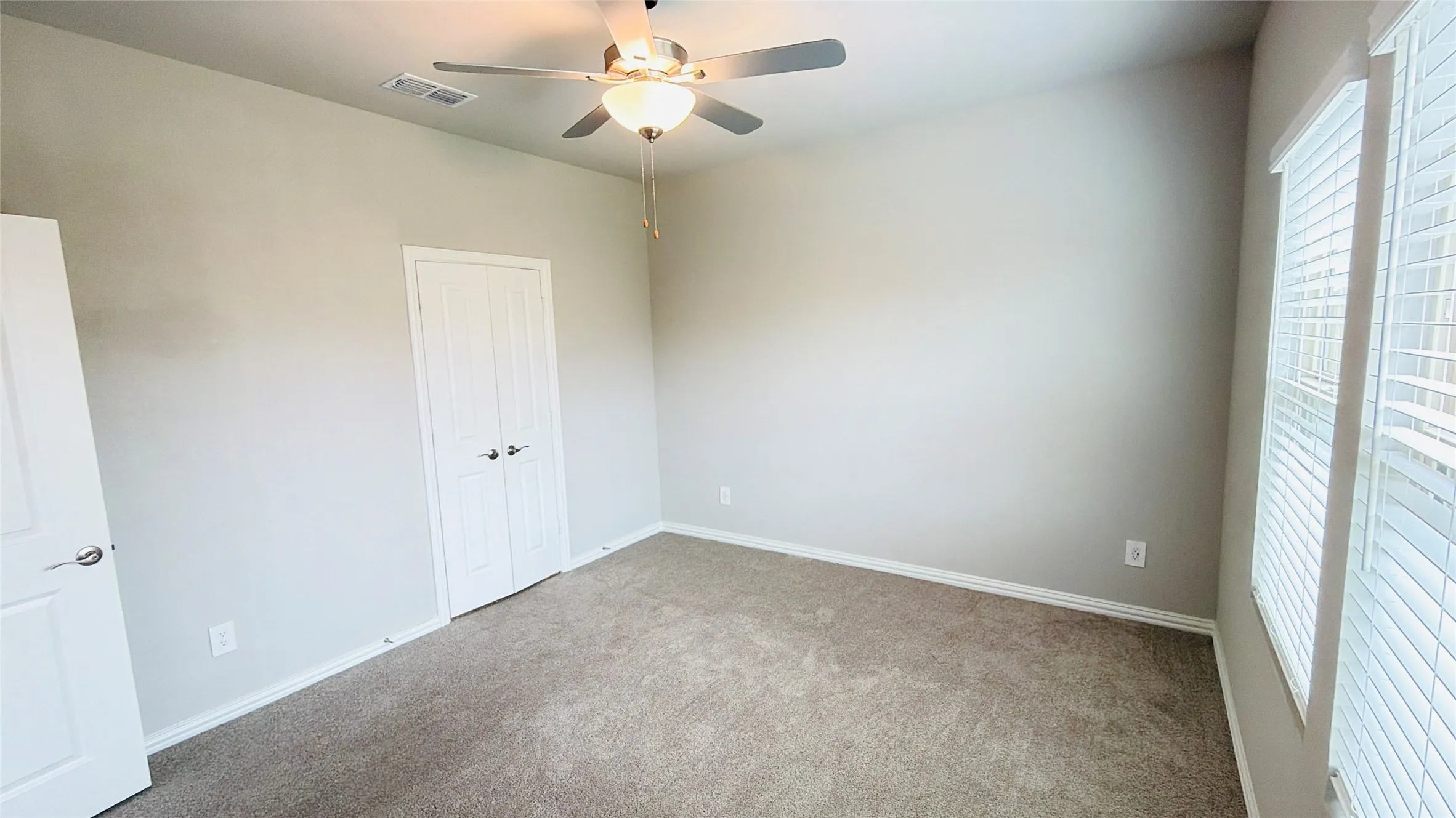 Carpeted flooring, ceiling fan with integrated lighting, window with blinds, and white panel doors