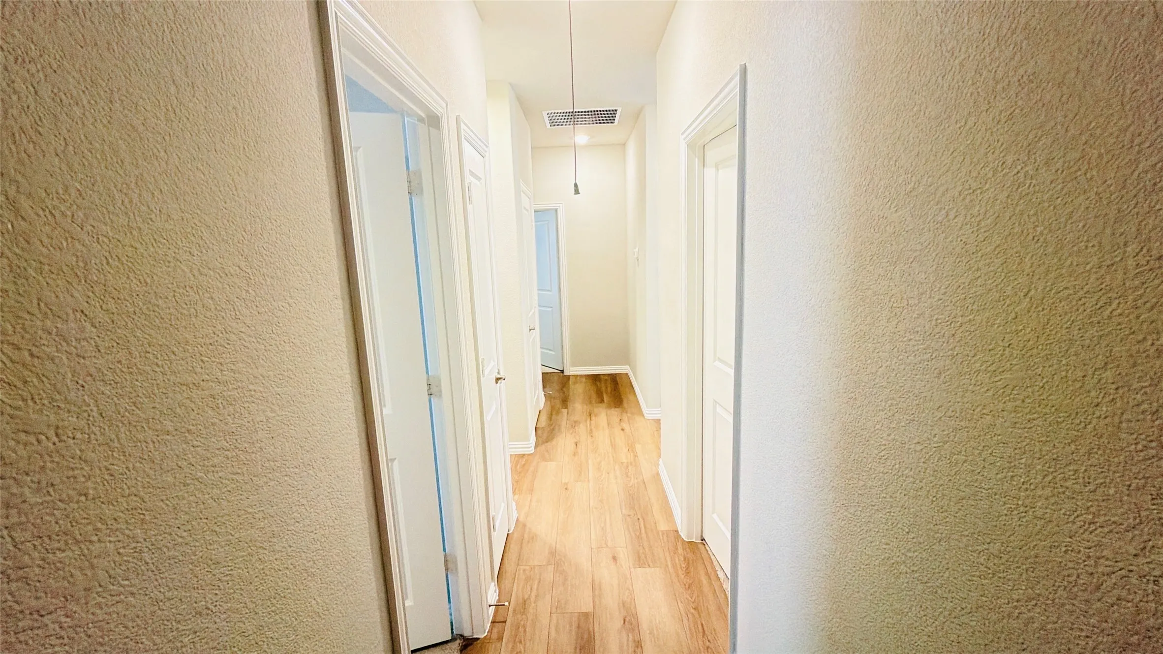 Hallway featuring wood-finish flooring, light-colored textured walls, and recessed lighting