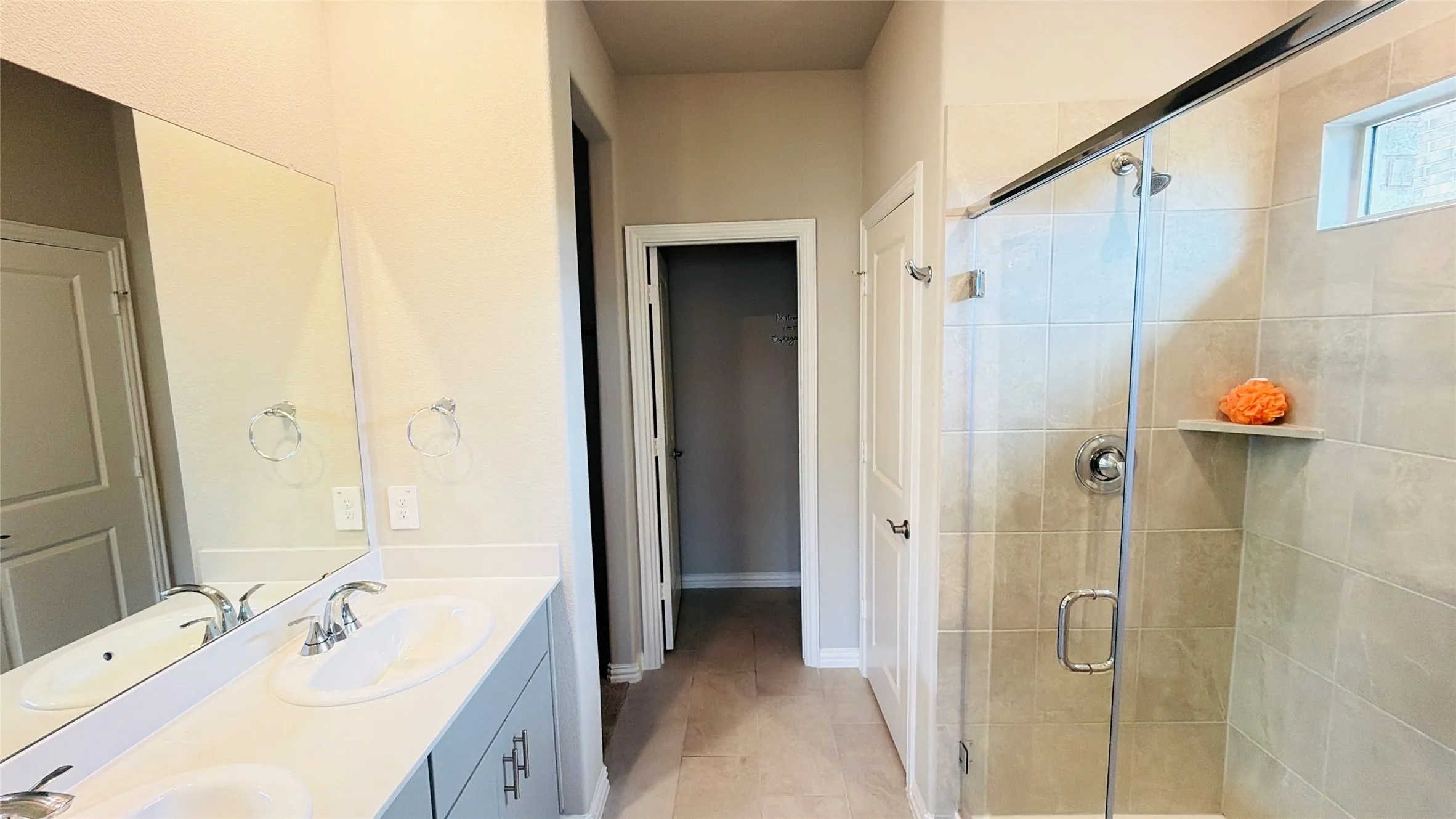Double vanity with integrated sinks, chrome fixtures, and light-toned cabinetry