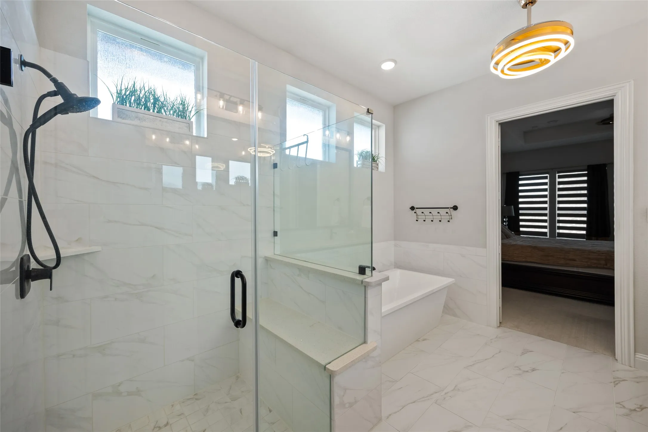 Glass-enclosed shower with matte black fixtures, separate soaking tub, and large format tile flooring