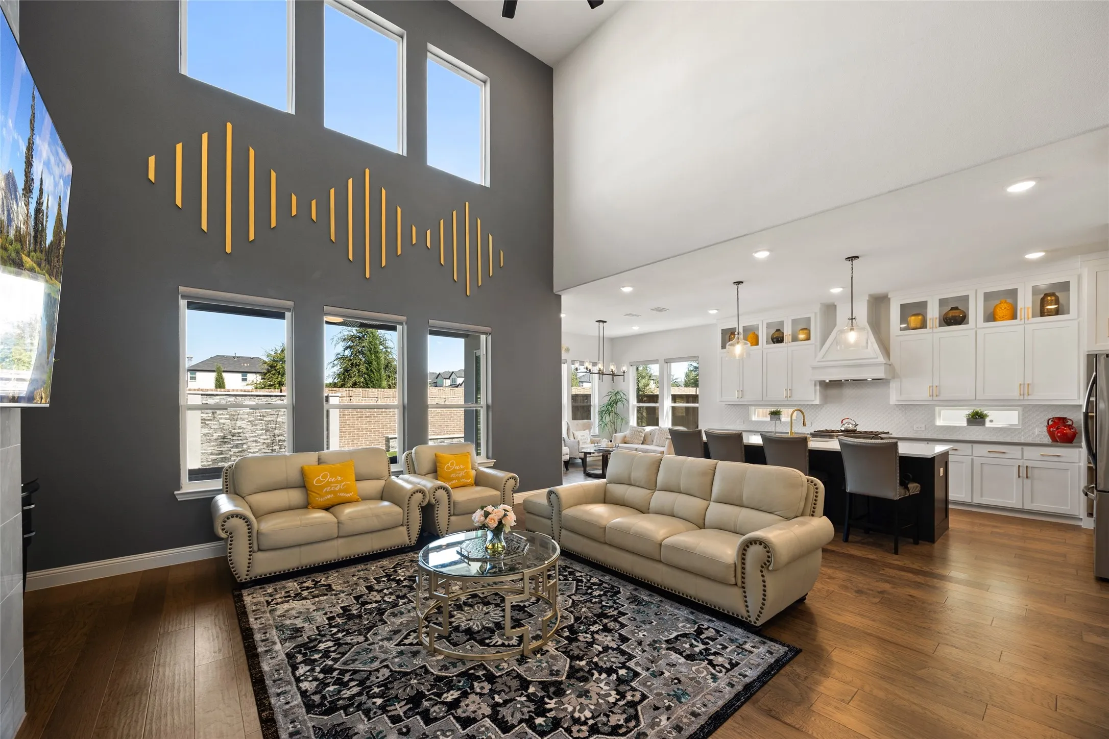 Vaulted ceiling, wood-finish flooring, white shaker cabinetry, kitchen island with seating, stainless steel appliances