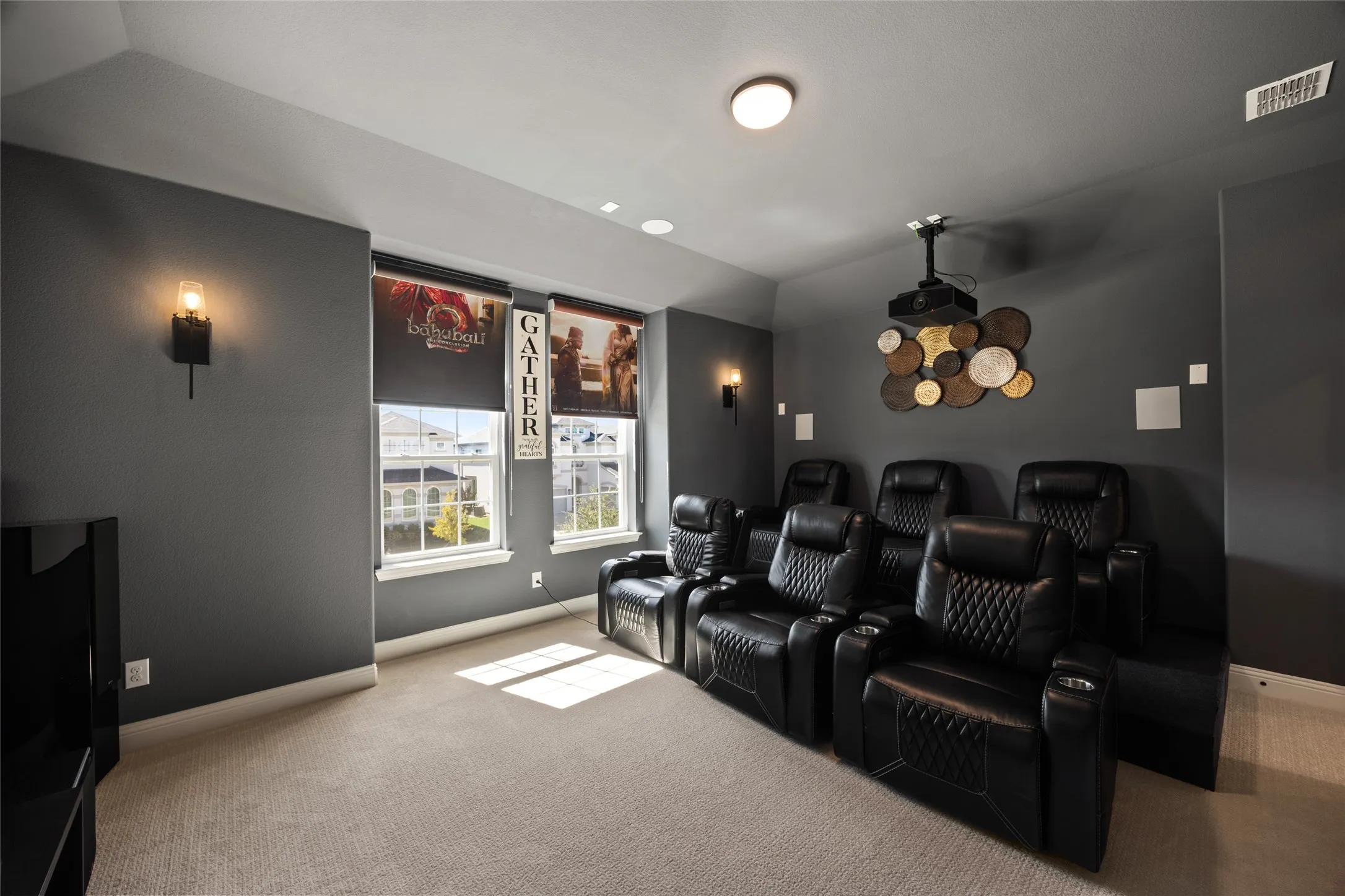 Dedicated media room with plush carpeting, wall-mounted sconces, and recessed ceiling lighting