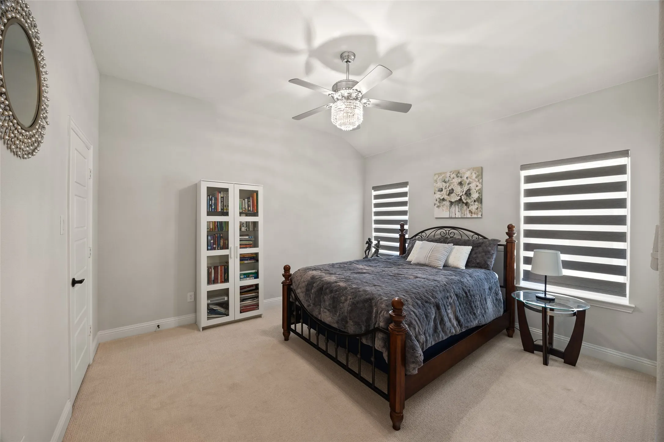 Vaulted ceiling with a contemporary ceiling fan, two windows with horizontal banded shades, and carpet flooring