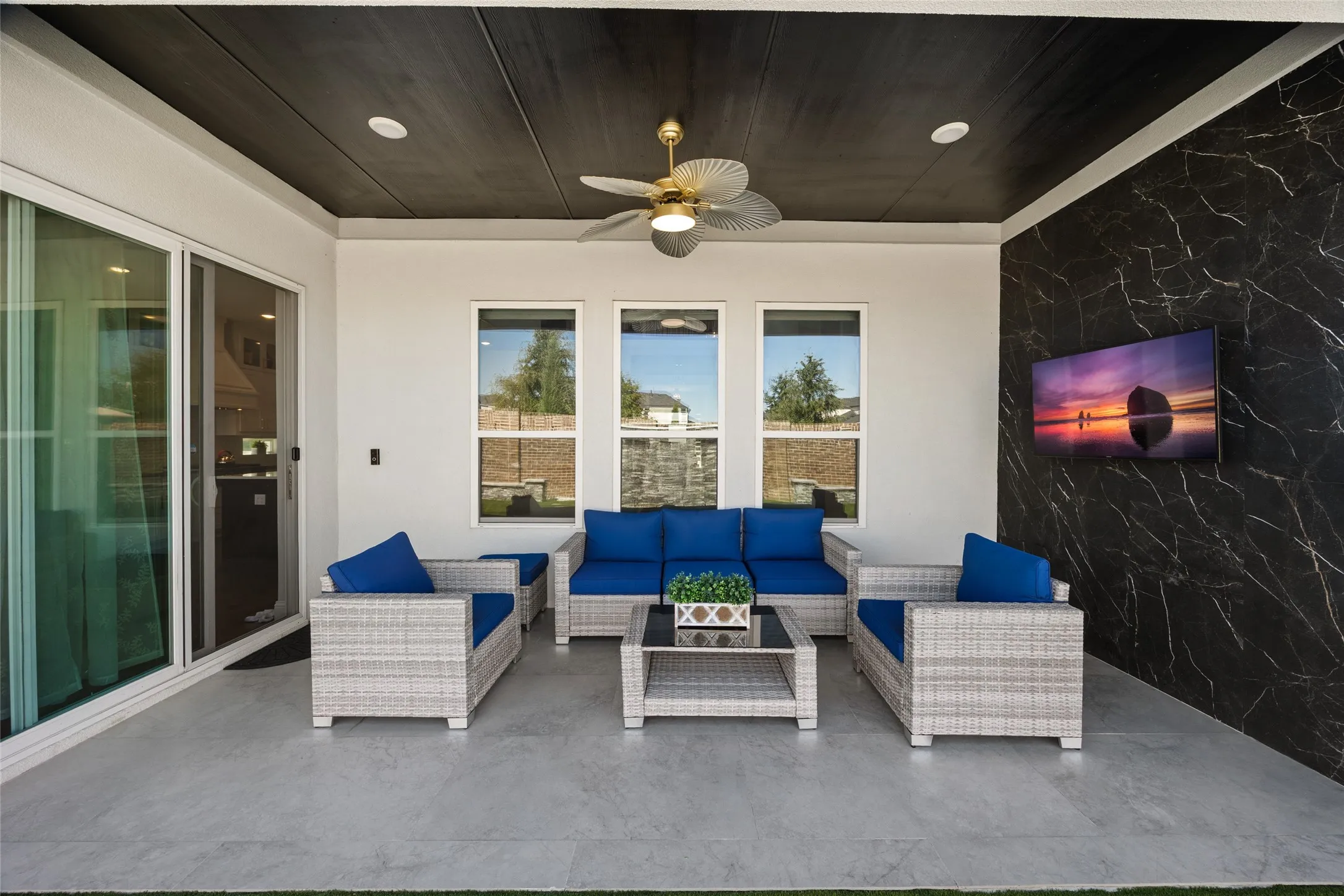 Covered patio featuring a dark wood-finish ceiling, mounted ceiling fan, tile flooring, and a decorative accent wall