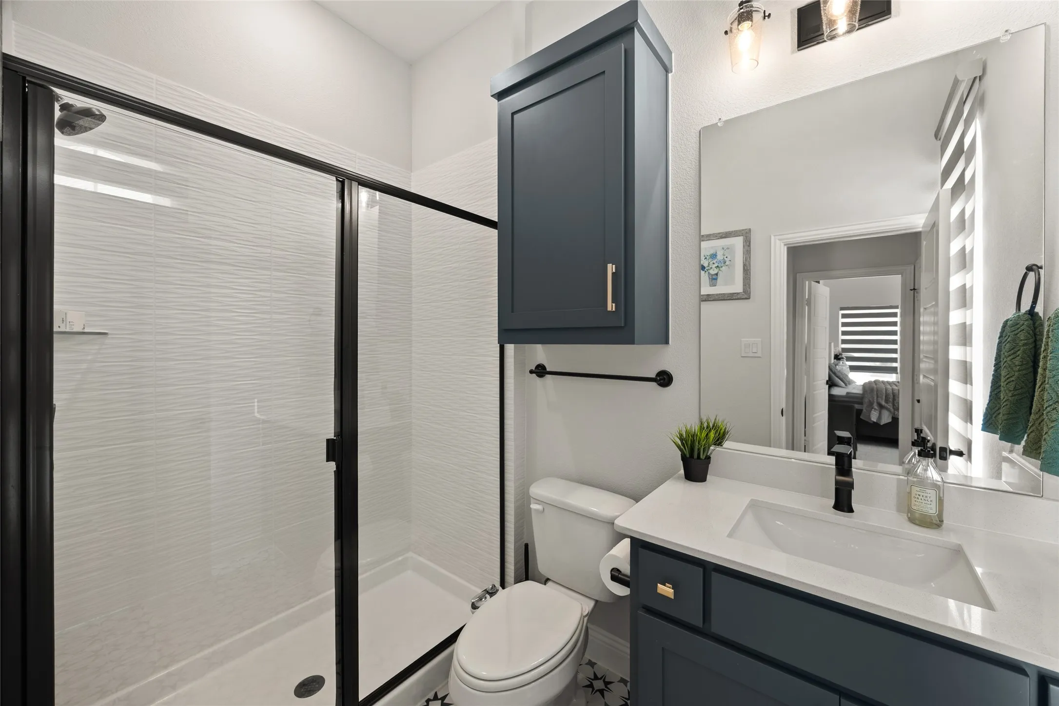 Shower with black-framed glass enclosure and textured white wall tile