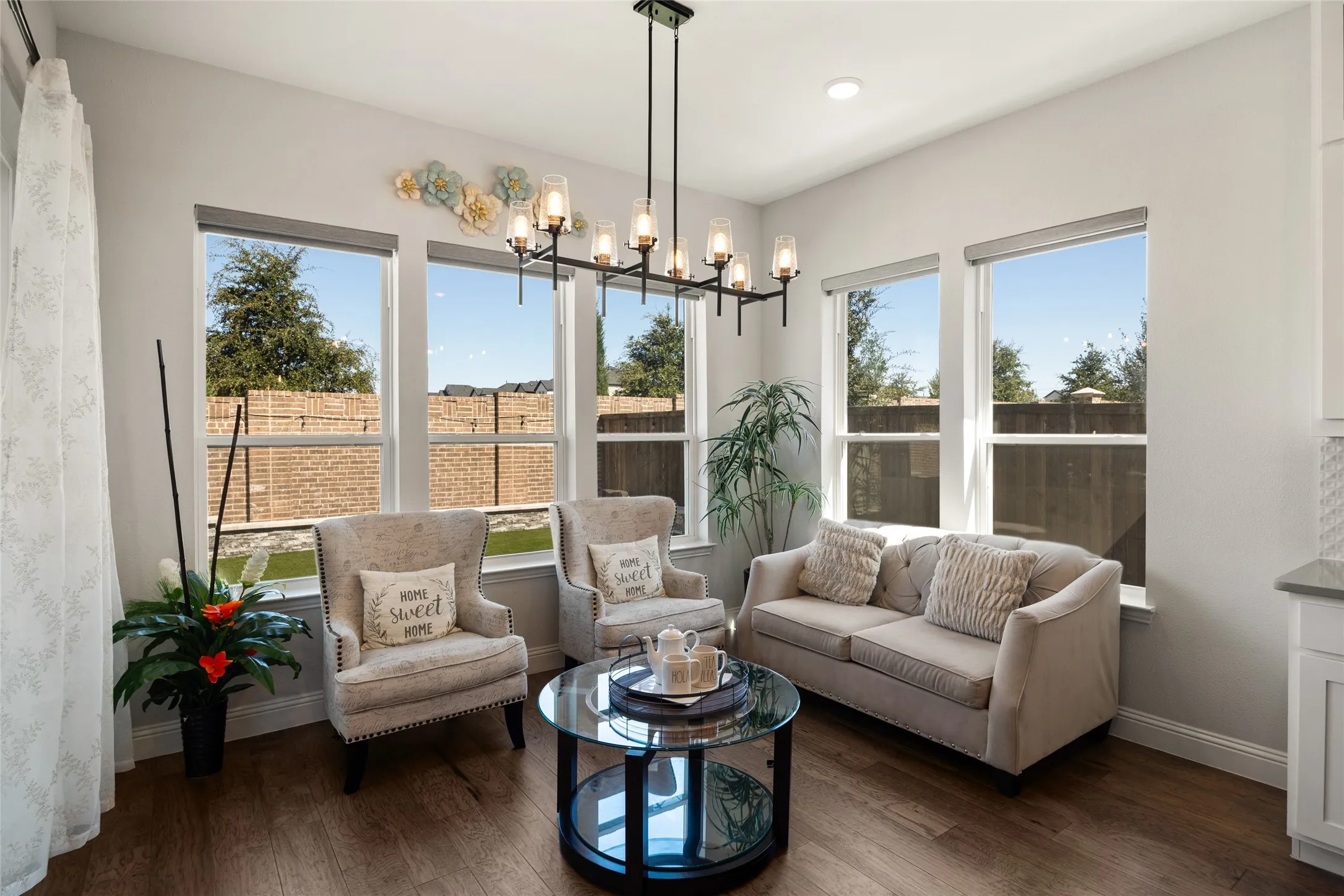 Wood-finish flooring, a linear chandelier, recessed lighting, multiple windows, and light-colored walls