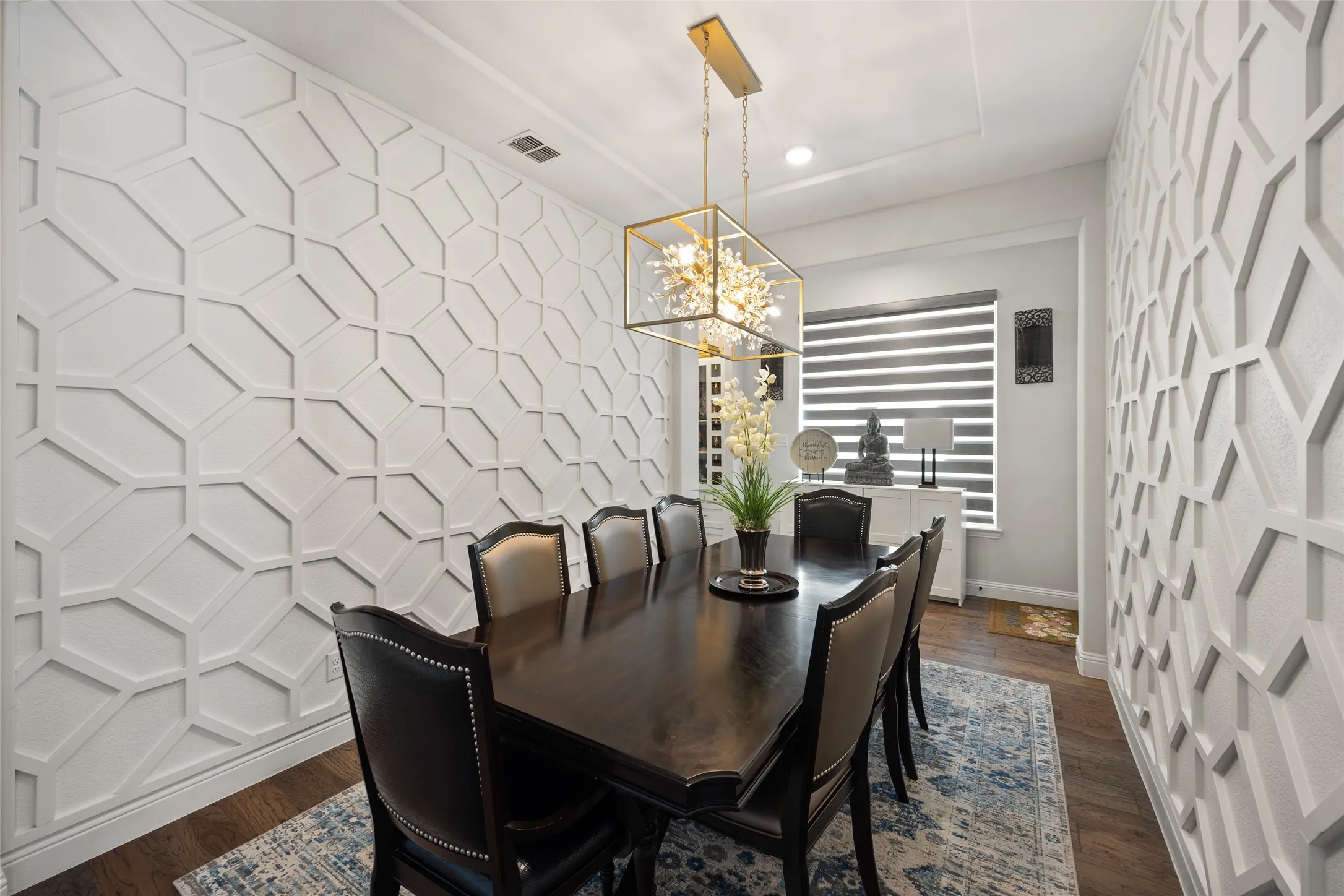 Decorative accent wall panels, recessed ceiling detail, and a modern rectangular chandelier