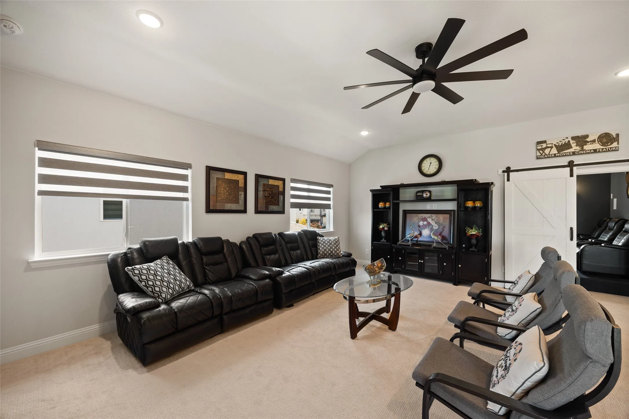 Vaulted ceiling, recessed lighting, modern ceiling fan, built-in entertainment center, and a barn door