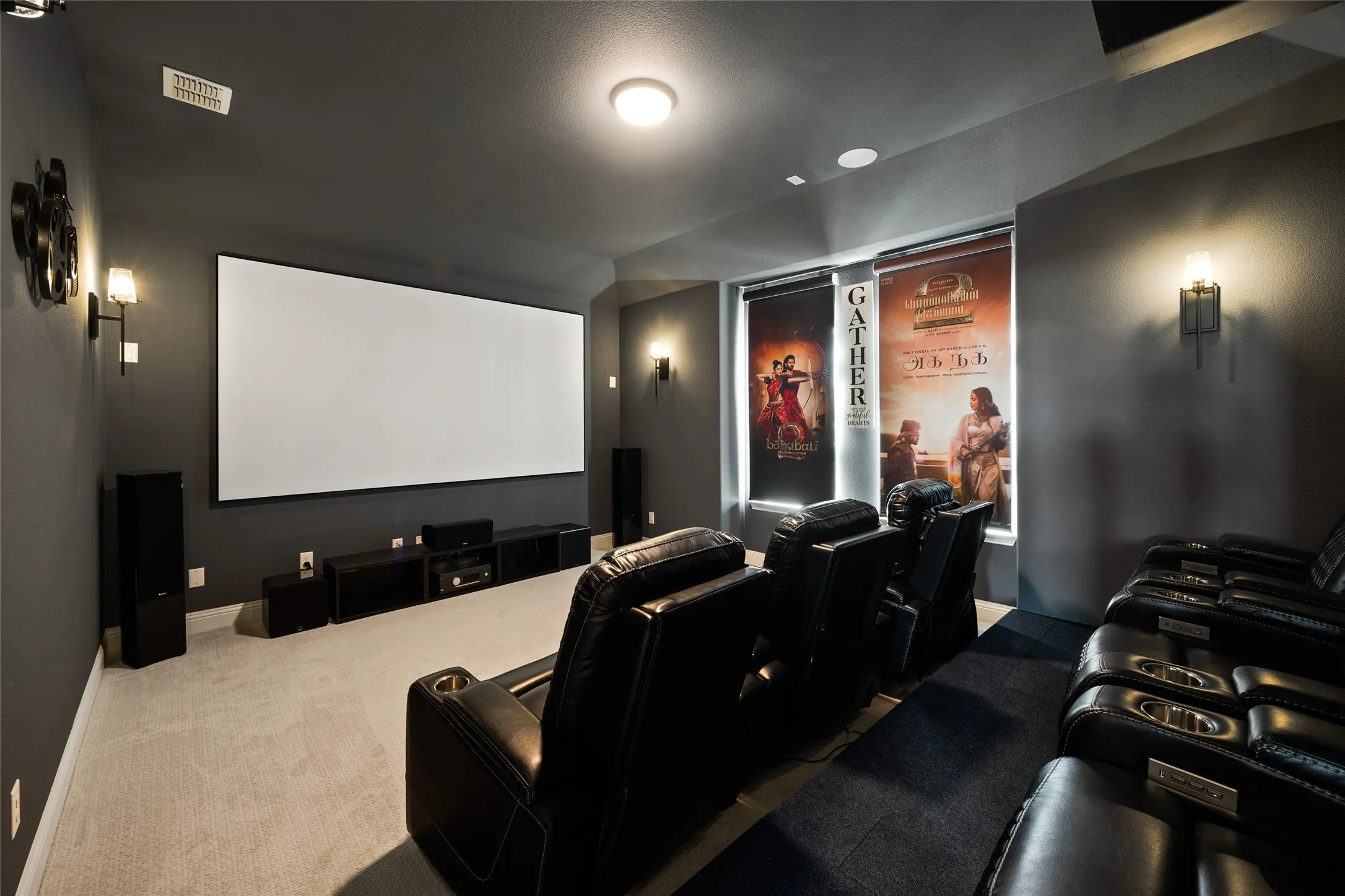 Large projection screen, built-in media console, wall-mounted sconce lighting, recessed ceiling lighting, and carpeted flooring