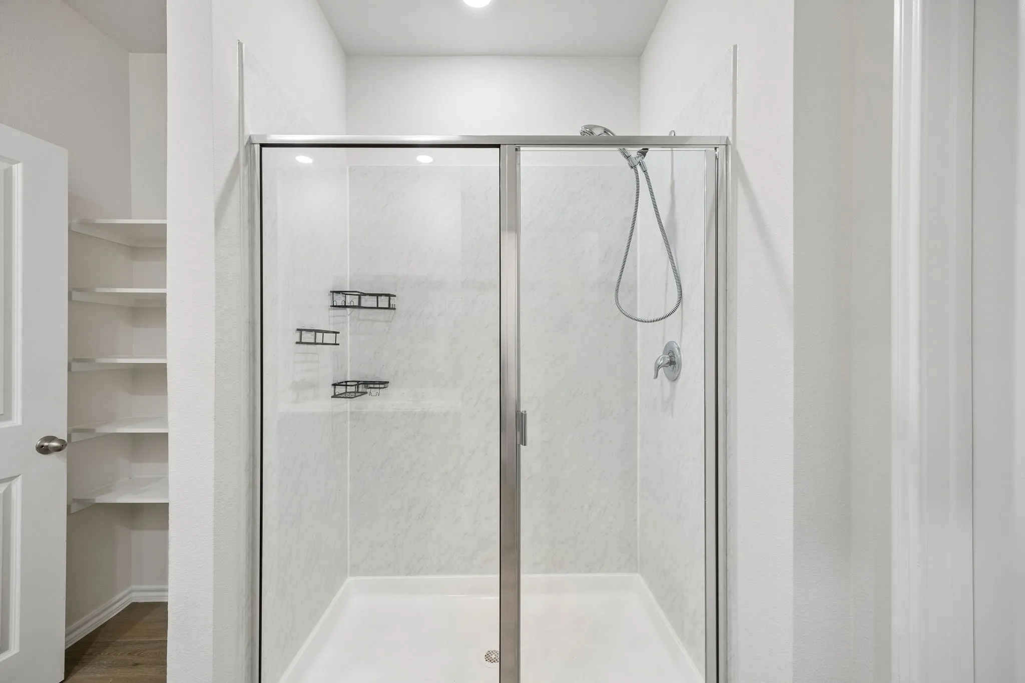 Walk-in shower with clear glass enclosure, notice the open storage to the left