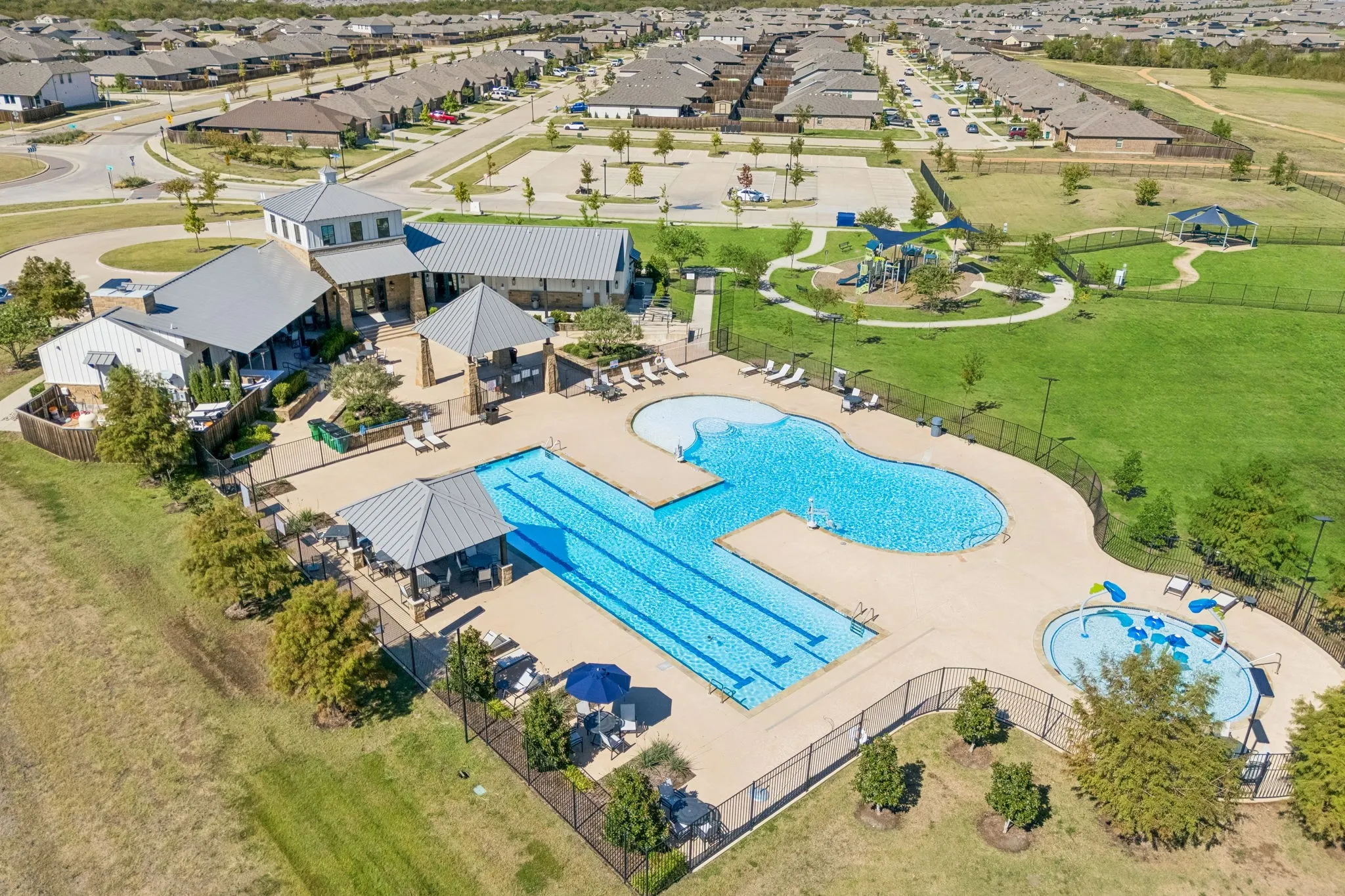 Community swimming pool with lap lanes, adjacent splash pad, and multiple covered cabanas