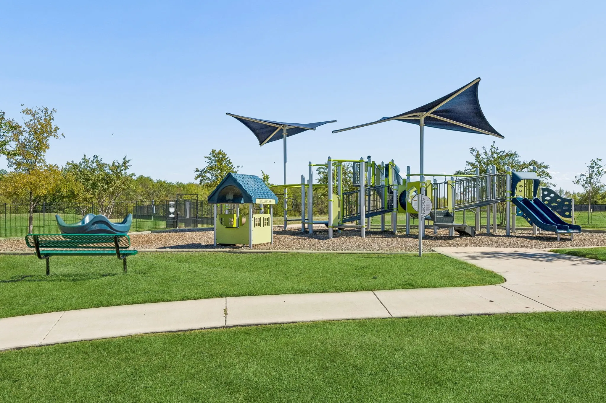 Community playground featuring multiple slides, climbing structures, and shade canopies