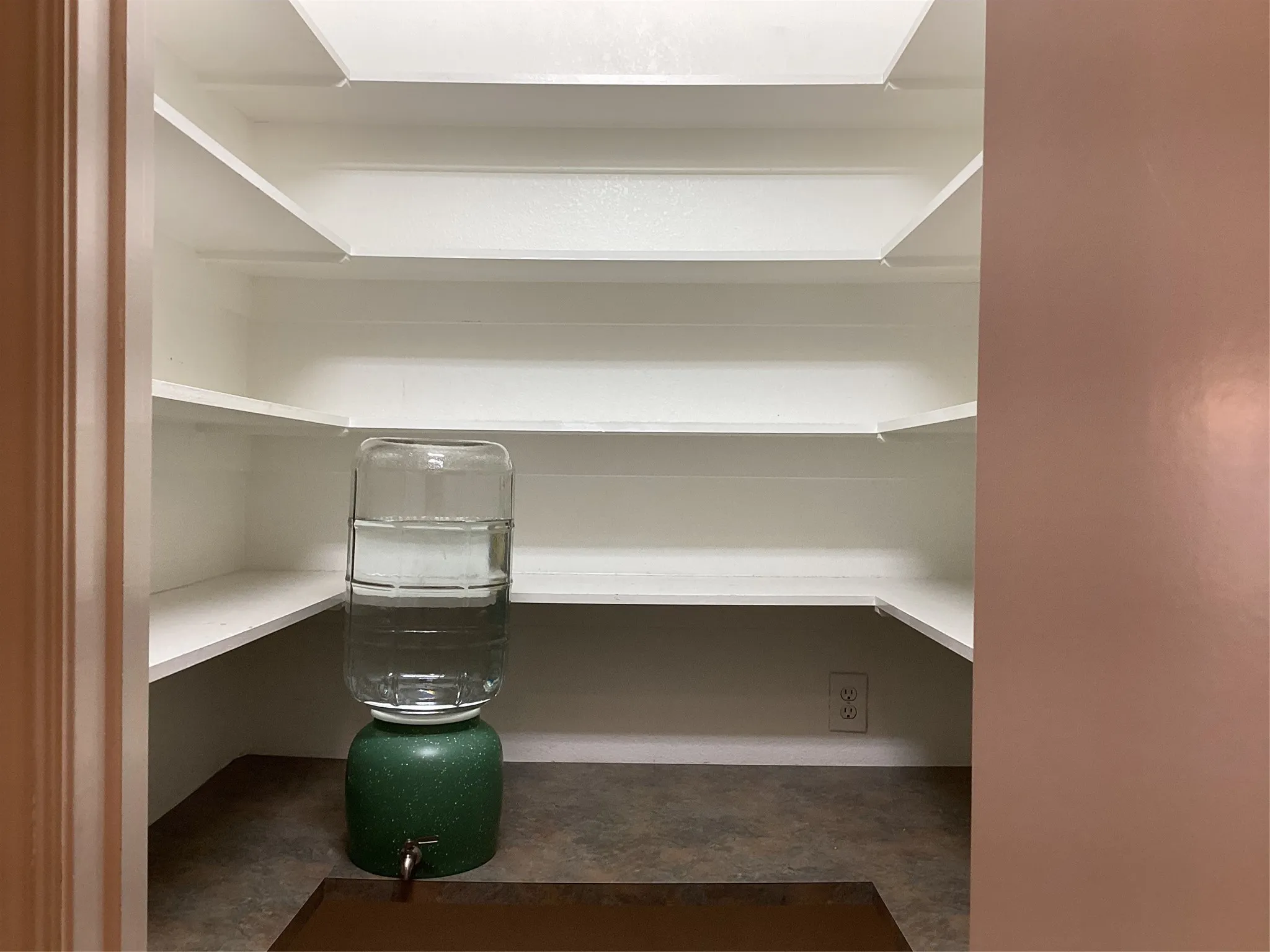 Built-in shelving with multiple levels, an electrical outlet, and durable flooring