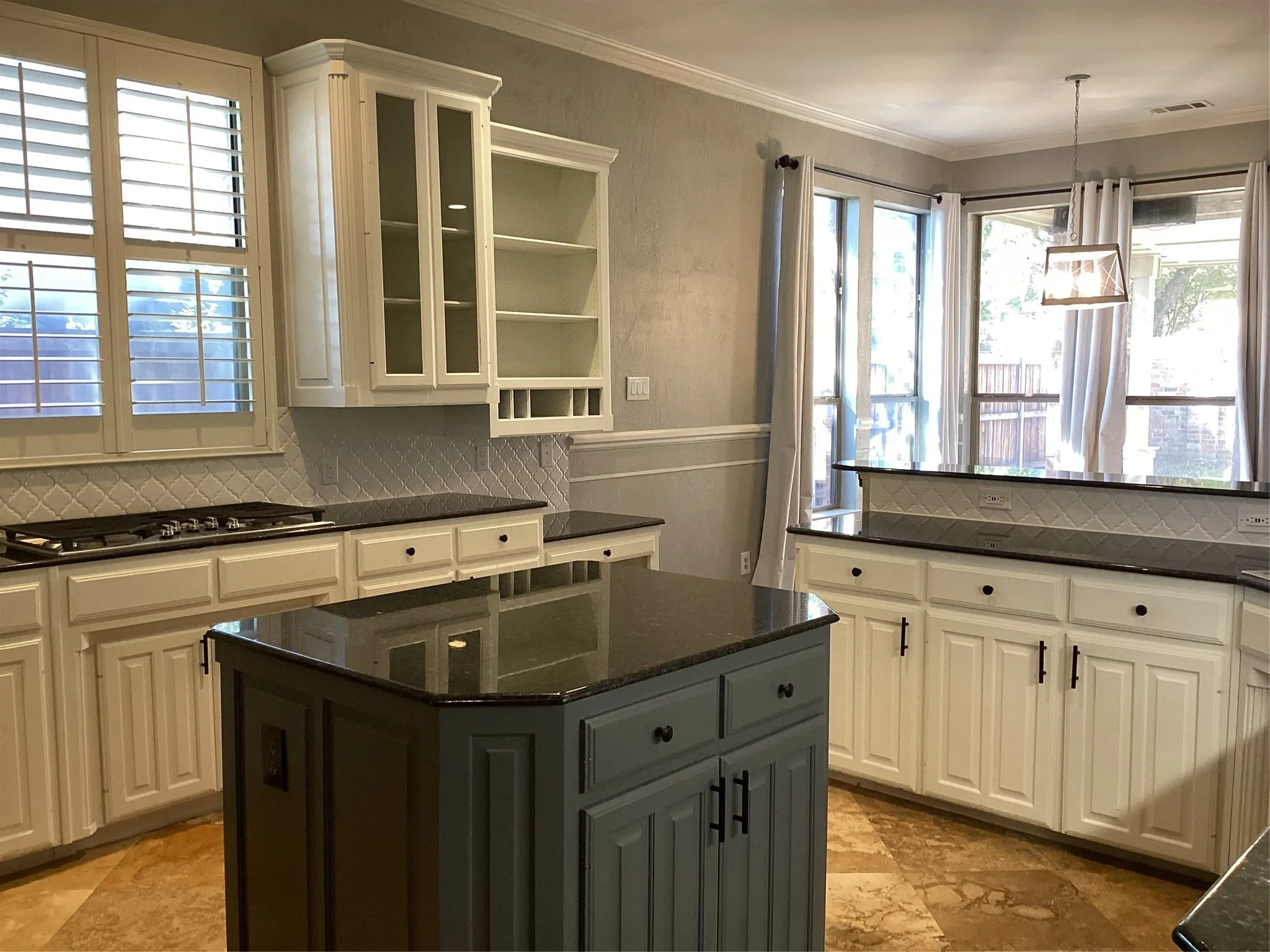 Kitchen featuring a central island, recessed panel cabinetry, black countertops, and a tile backsplash