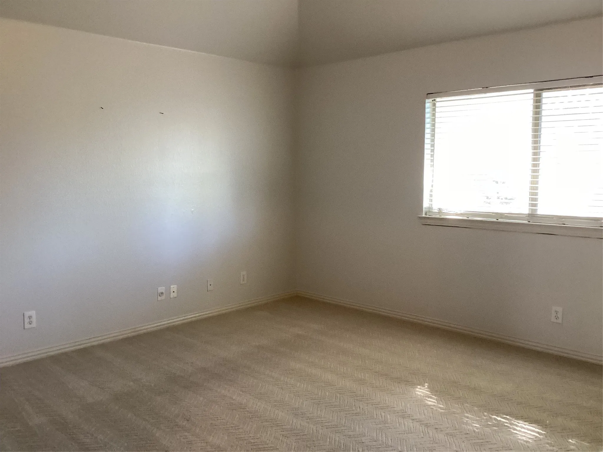 Carpeted flooring, vaulted ceiling, and a large window with horizontal blinds