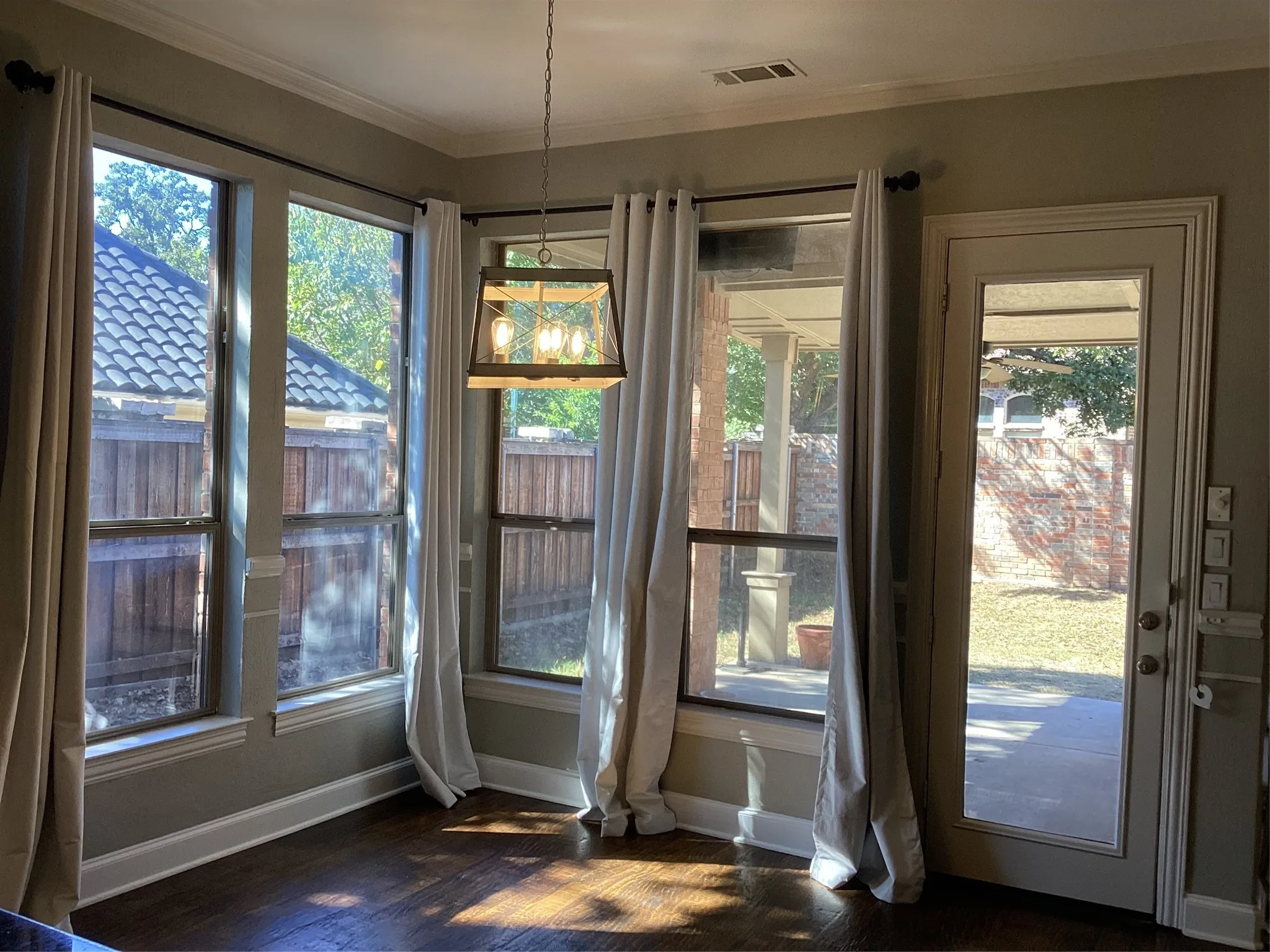 Wood-finish flooring, multiple windows, a glass-paned door, and a decorative pendant light fixture