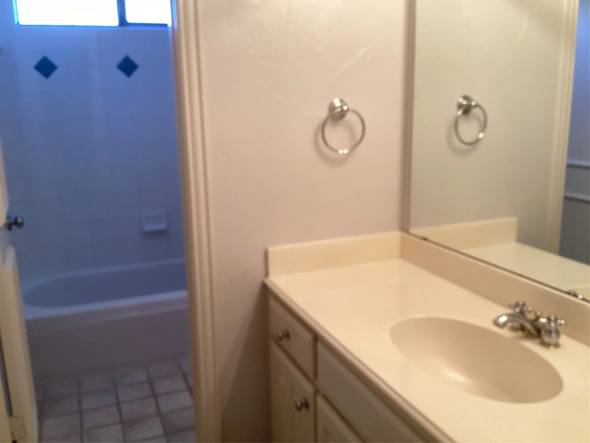 Vanity with an integrated sink and chrome faucet, large wall mirror, and a full-size bathtub with tiled walls