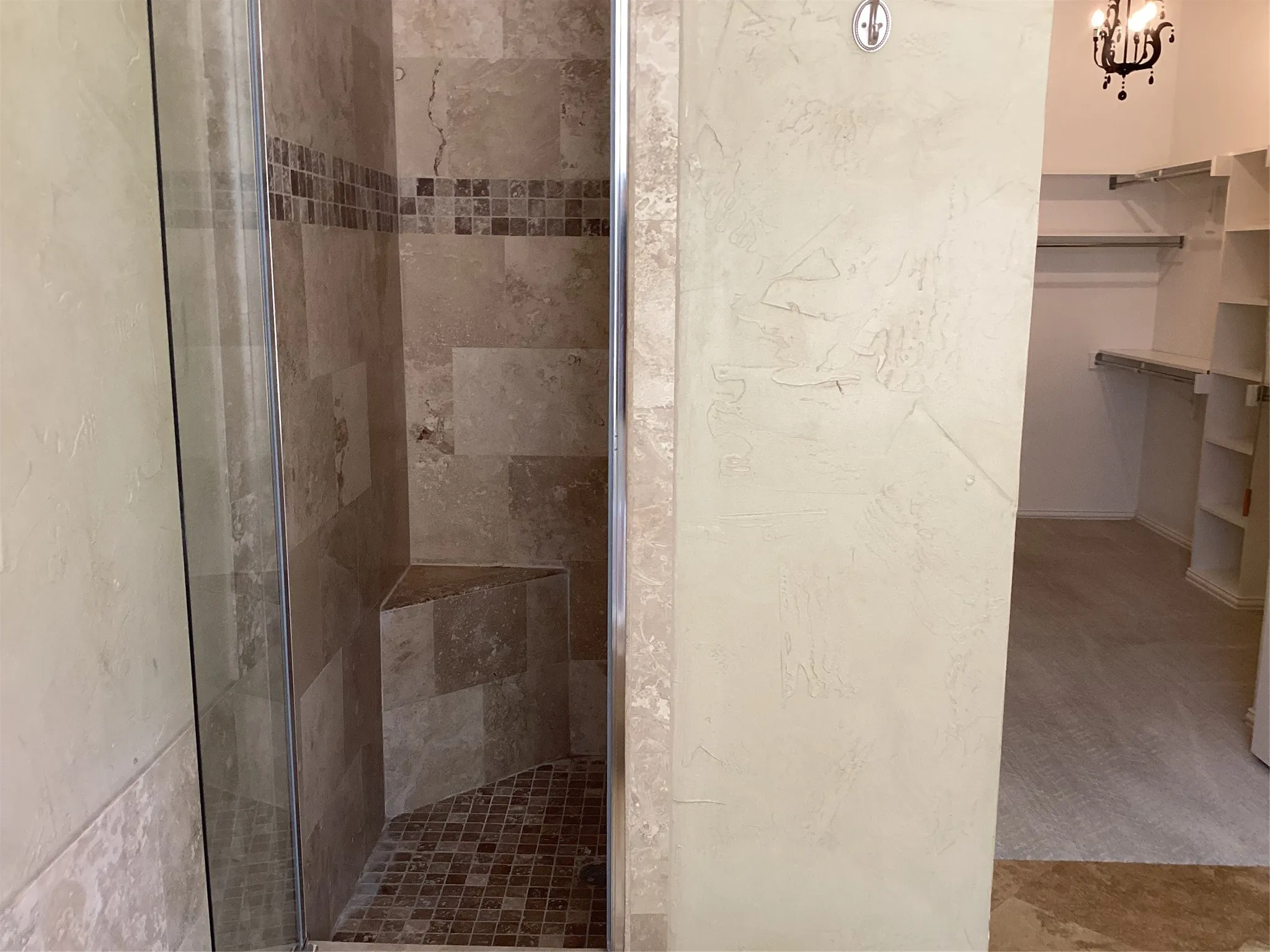 Glass-enclosed shower with a built-in bench, mosaic tile floor, and large format wall tiles