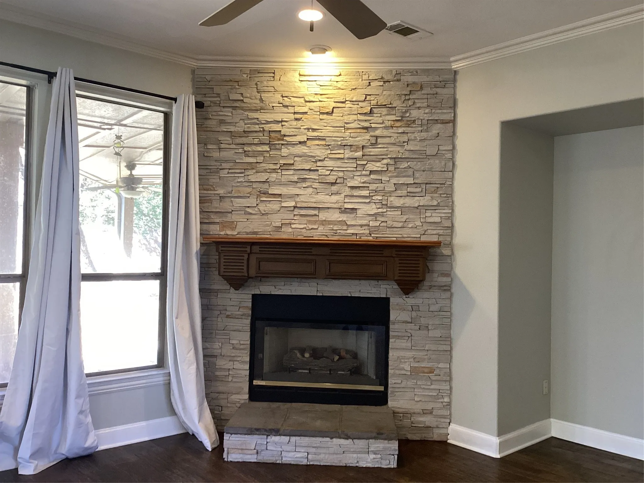 Stacked stone fireplace with a dark wood mantel and hearth