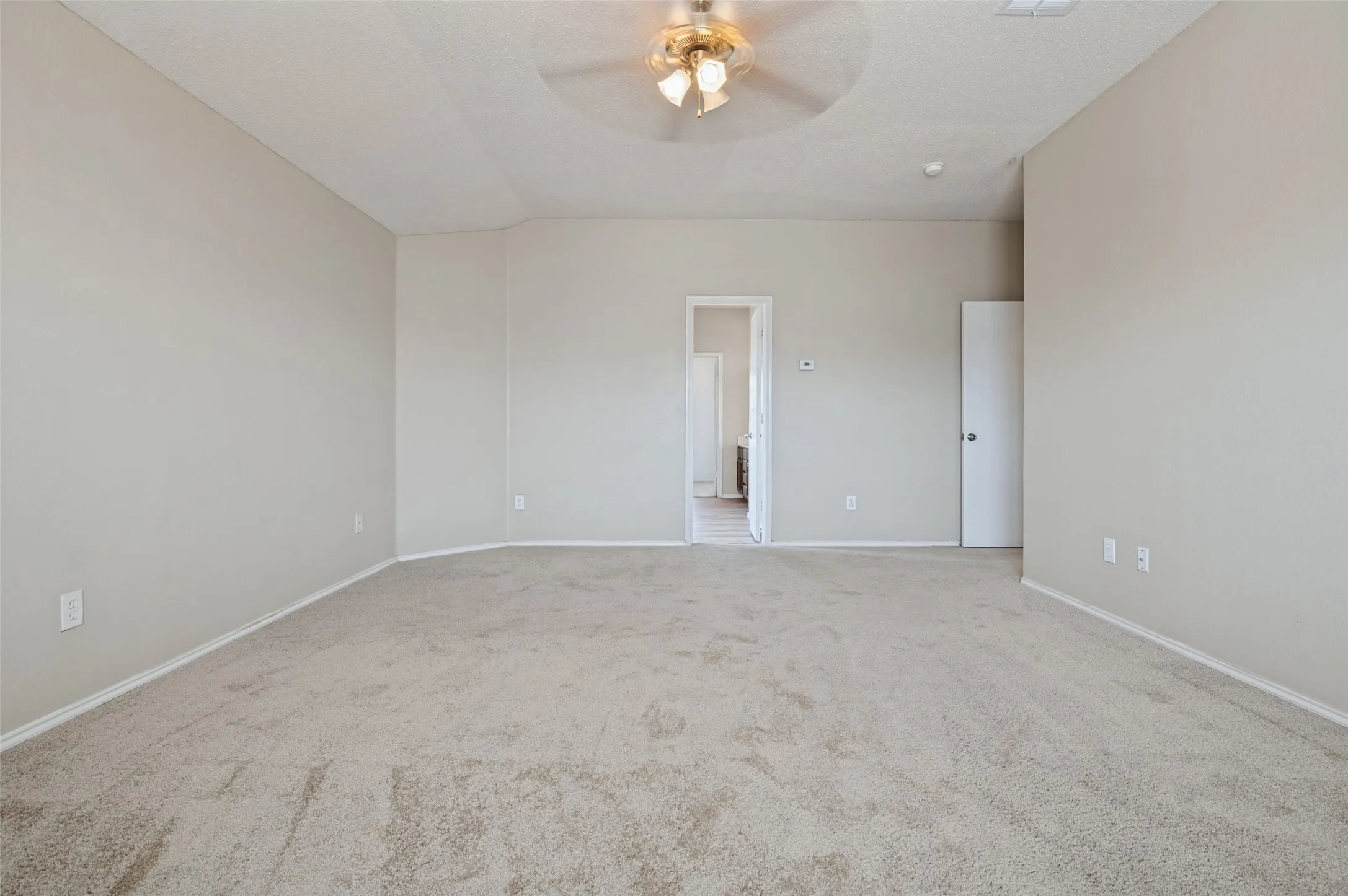 Tray ceiling with a decorative ceiling fan, wall-to-wall carpeting, and neutral paint