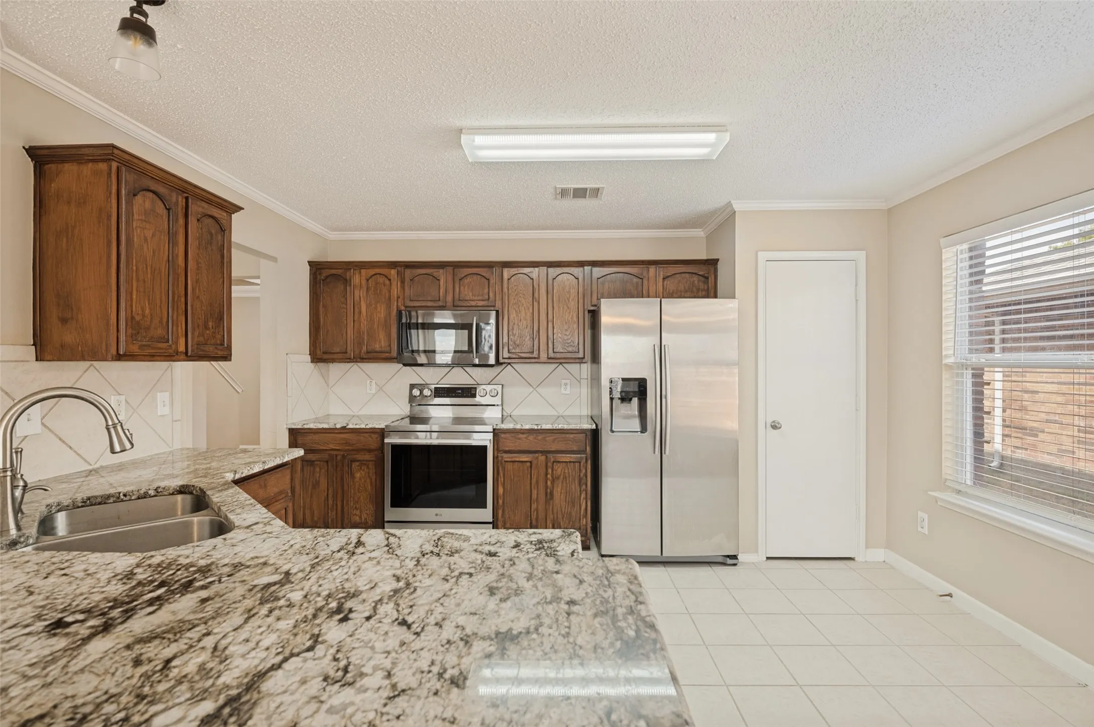 Kitchen featuring wood cabinetry, stainless steel appliances, and a double basin sink