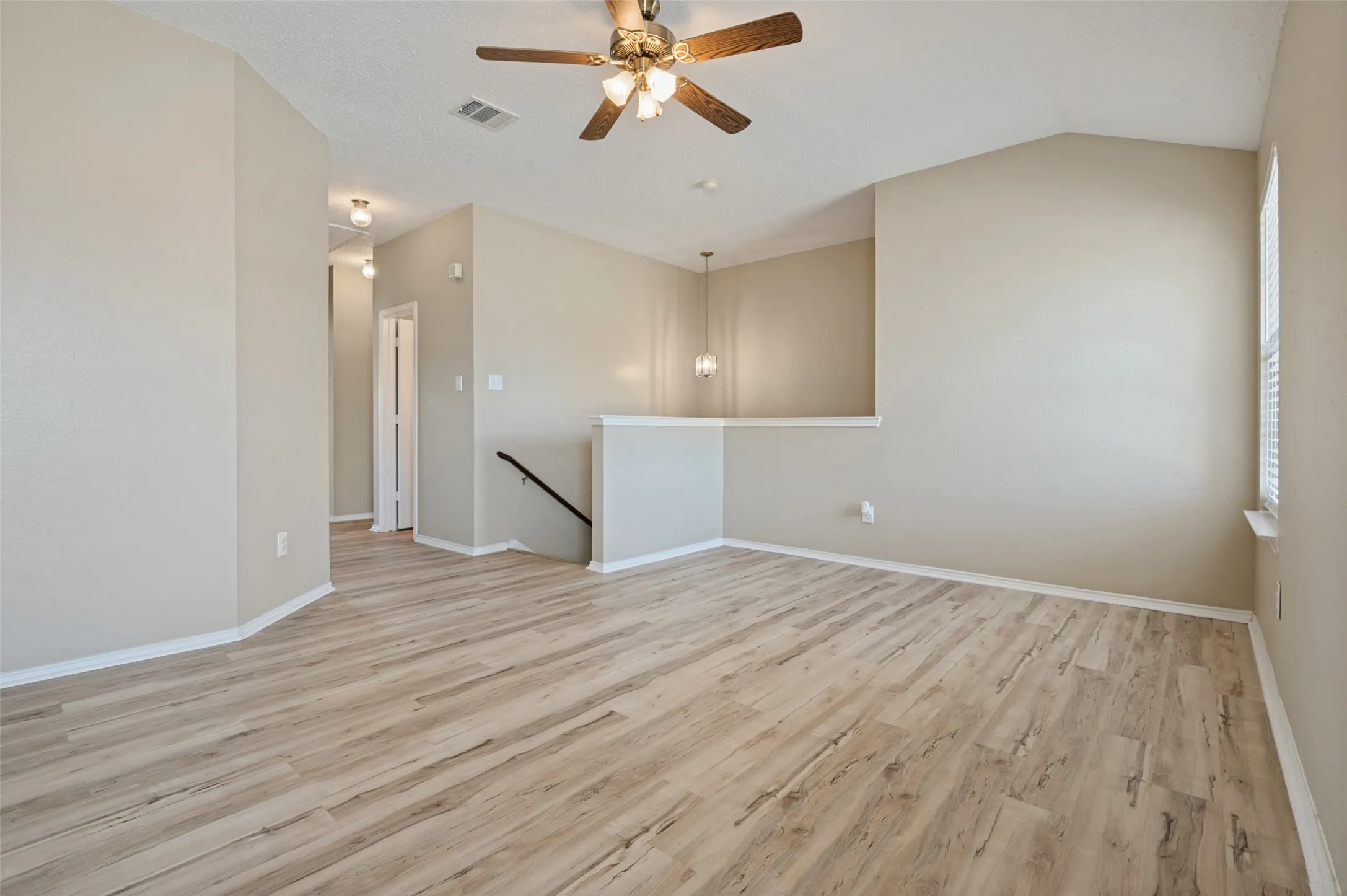 Vaulted ceiling with a ceiling fan, wood-finish flooring, and neutral wall tones