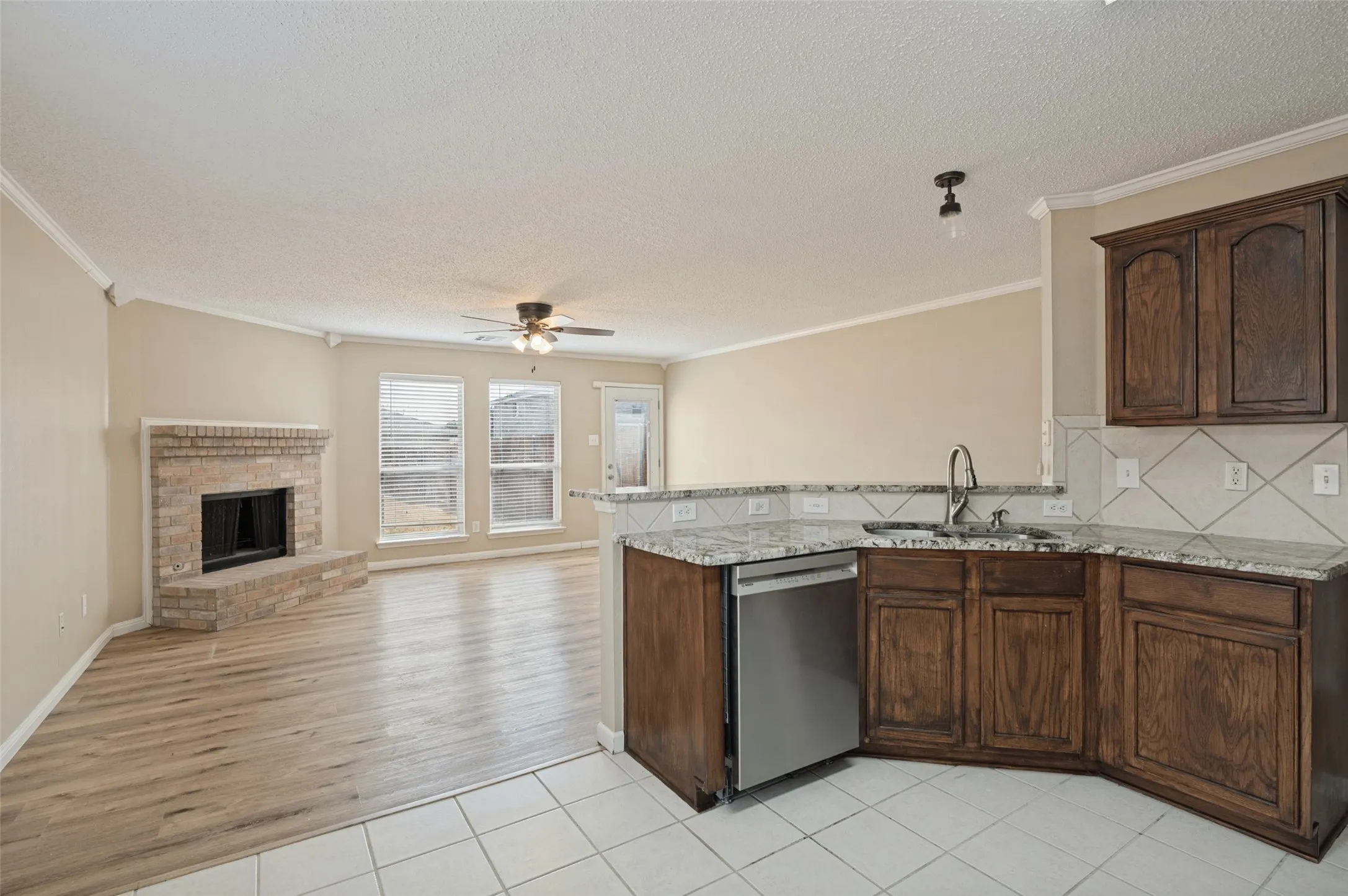 Kitchen featuring granite countertops, wood cabinetry, stainless steel dishwasher, and a tile backsplash
