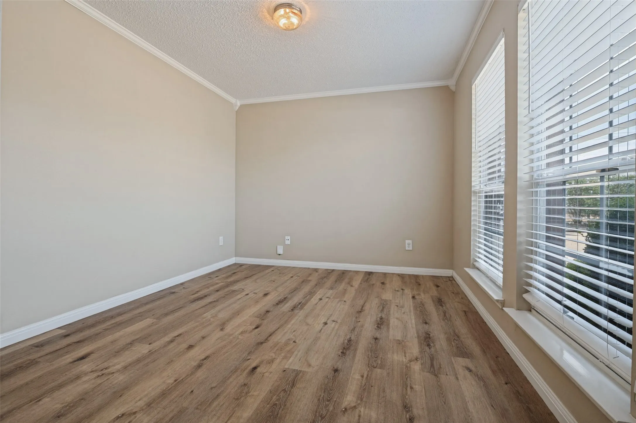 Wood-finish flooring, neutral wall paint, white crown molding, white window trim, and white horizontal blinds