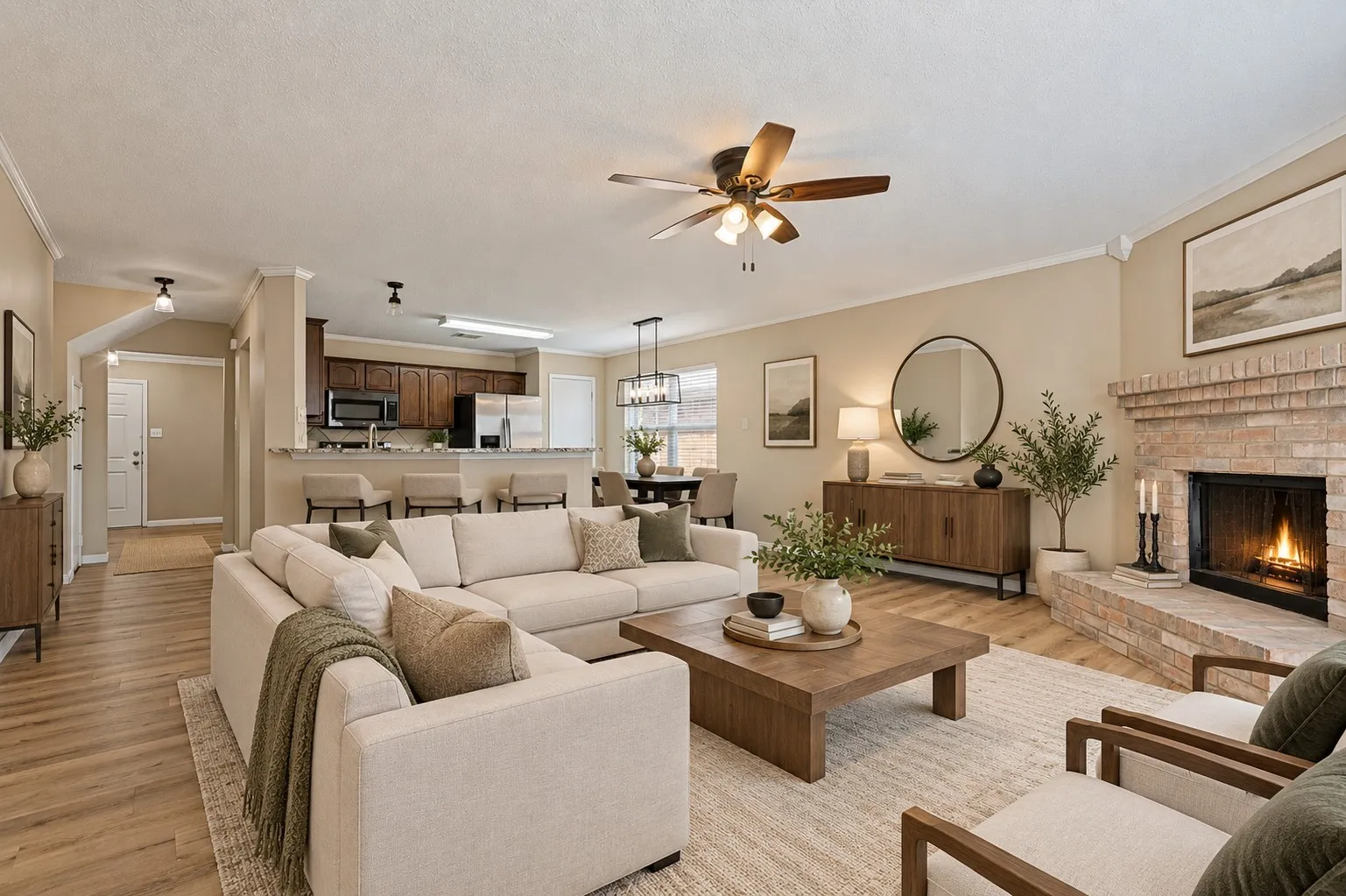 Open-concept living area with wood-finish flooring, a brick fireplace, and a ceiling fan