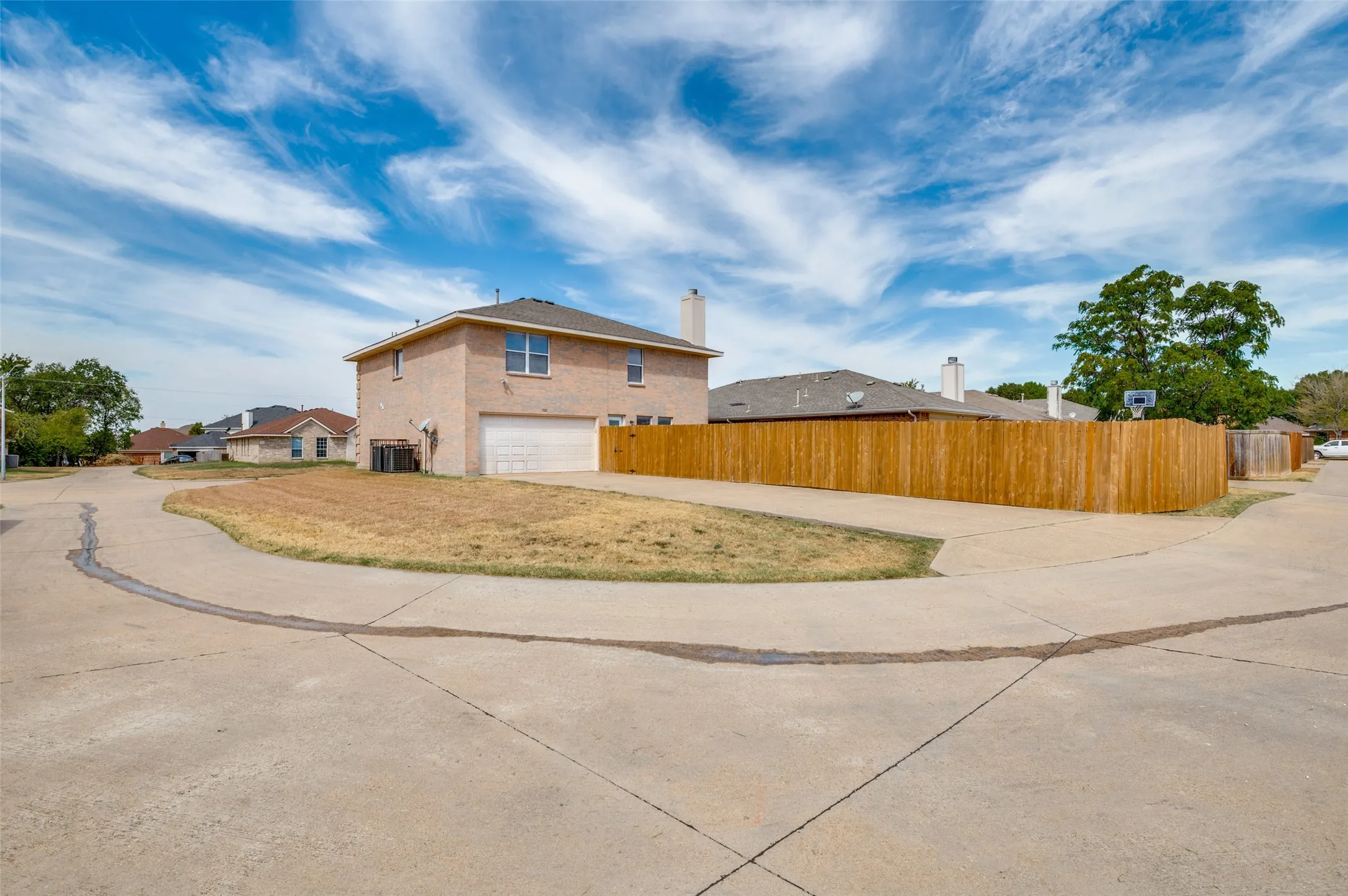 Brick exterior construction with an attached garage, a wooden privacy fence, and a concrete driveway